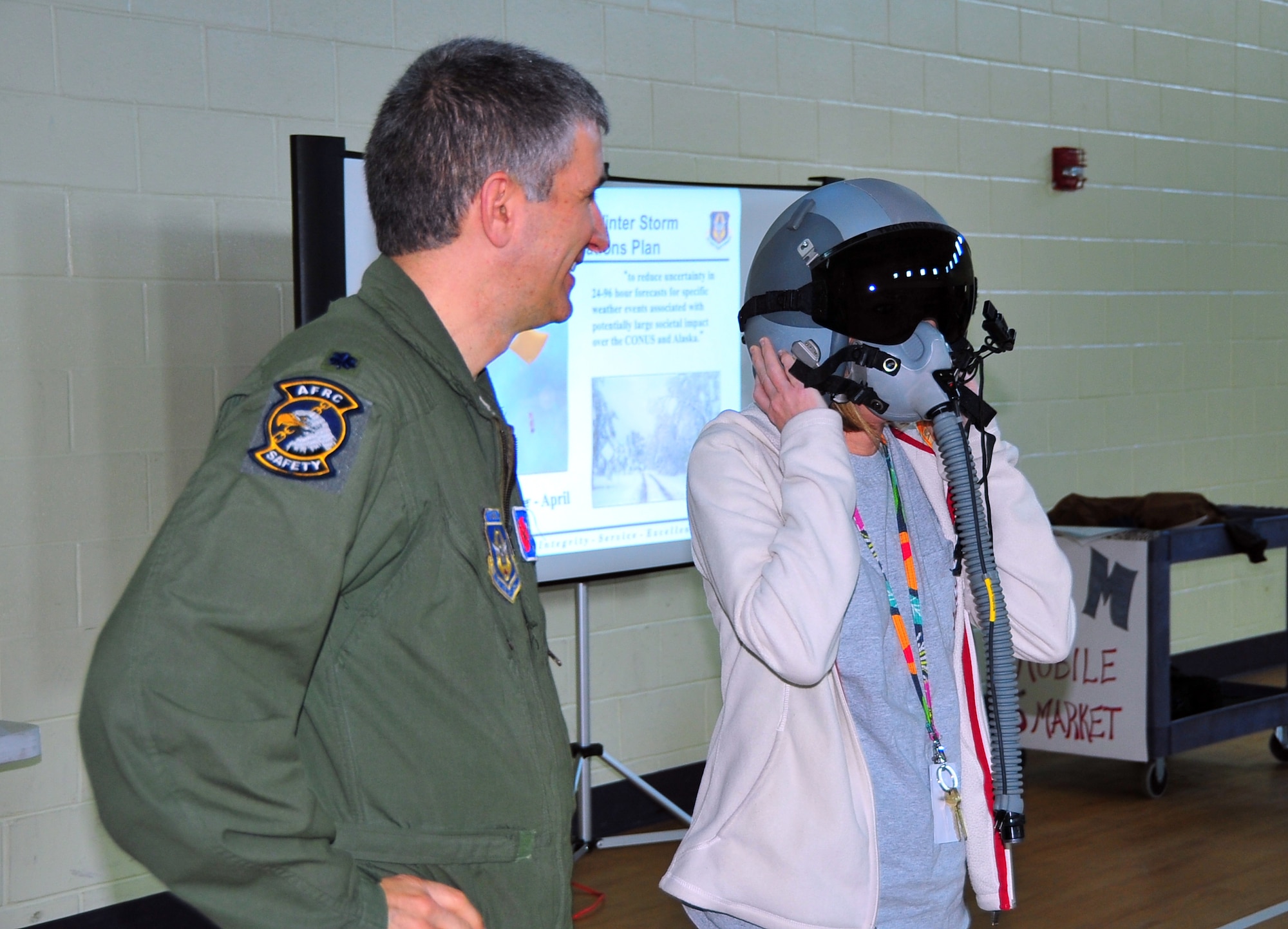 Cindy Hathcock, a 4th grade math teacher at Harper McCaughan Middle School, Long Beach, Miss., tries on a flight helmet during a Hurricane Hunter briefing March 7. Pilots Lt. Col. Jeffrey Ragusa and Lt. Col. Shannon Hailes briefed 224 students about the 53rd Weather Reconnaissance Squadron mission. (U.S. Air Force photo/Maj. Marnee A.C. Losurdo)