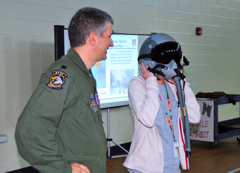 Cindy Hathcock, a 4th grade math teacher at Harper McCaughan Middle School, Long Beach, Miss., tries on a flight helmet during a Hurricane Hunter briefing March 7. Pilots Lt. Col. Jeffrey Ragusa and Lt. Col. Shannon Hailes briefed 224 students about the 53rd Weather Reconnaissance Squadron mission. (U.S. Air Force photo/Maj. Marnee A.C. Losurdo)