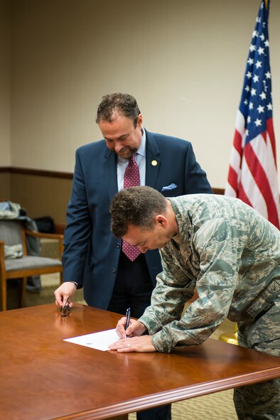 U.S. Air Force Col. Chad Franks, 23d Wing commander, and Dr. William McKinney, Valdosta State University president, formalize a partnership agreement at Moody Air Force Base, Ga., March 6, 2014. The agreement established an internship program in which two senior students will work with the 23d Medical Group each academic semester. This new working relationship was formed as part of the Air Force community partnership initiative and is the first of its kind within the Air Force. (U.S. Air Force photo by Airman 1st Class Ryan Callaghan/Released)