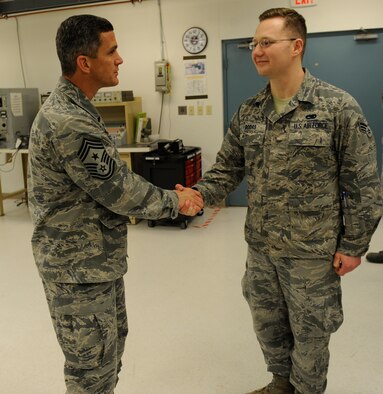 U.S. Air Force Chief Master Sgt. Richard Parsons, Air Combat Command command chief, coins Senior Airman Pedro Rodas, 7th Maintenance Group avionics technician, March 5, 2014, at Dyess Air Force Base, Texas. Rodas lead Parsons and his entire party through the 7th MXG avionics flight. (U.S. Air Force photo by Airman 1st Class Alexander Guerrero/Released)