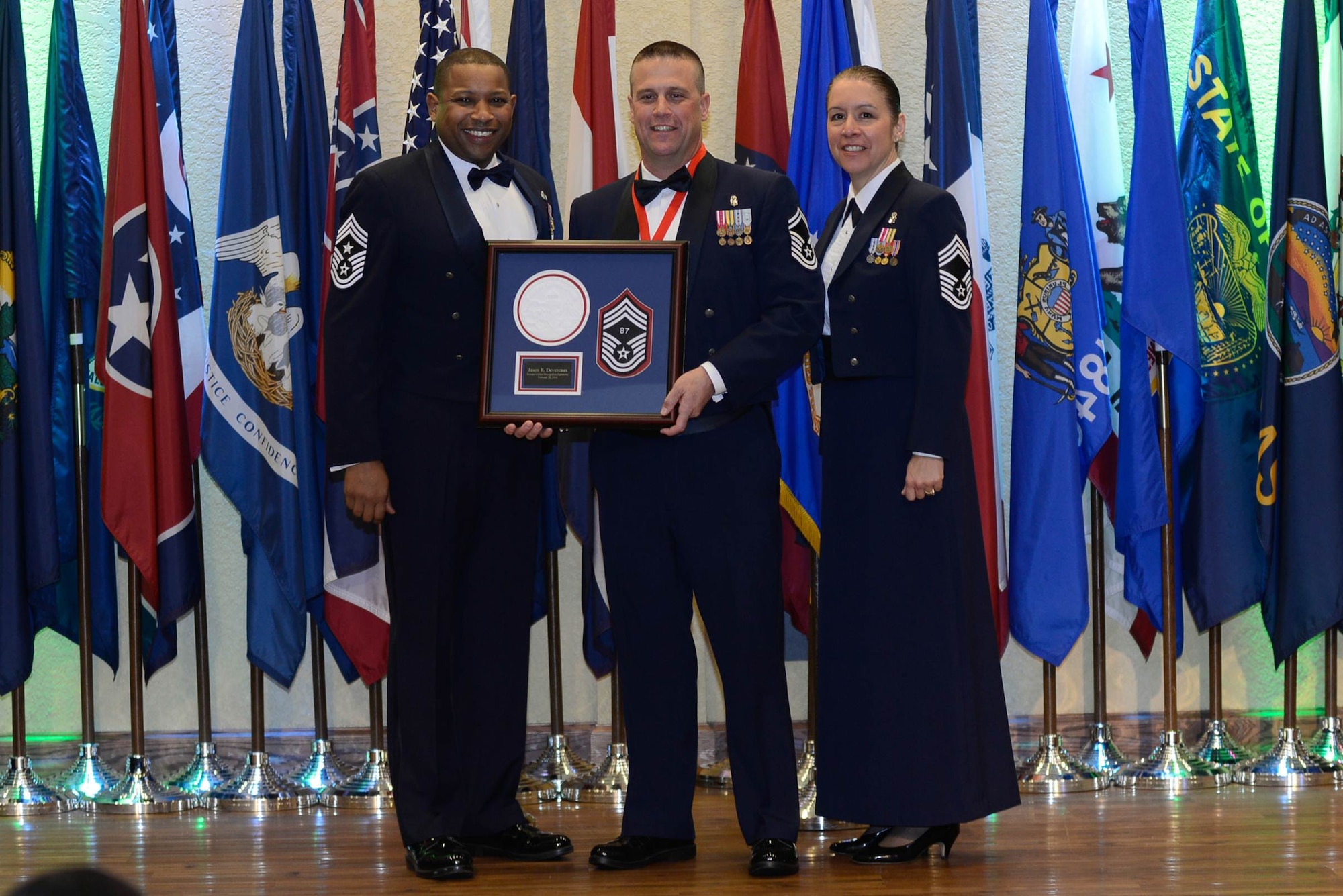 Senior Master Sgt. Jason Devereaux, 81st Aerospace Medicine Squadron, receives his honoree gift which was presented by Chief Master Sgts. Farrell Thomas, 81st Training Wing command chief, and Paula Eischen, 81st Diagnostic and Therapeutics Squadron and Keesler Chiefs Group president, during the Chiefs Recognition Ceremony Feb. 28, 2014, at the Bay Breeze Event Center, Keesler Air Force Base, Miss.  Keesler had four Airmen that were honored for attaining the rank of chief master sergeant. (Courtesy photo by Airman 1st Class Andrew Achong)