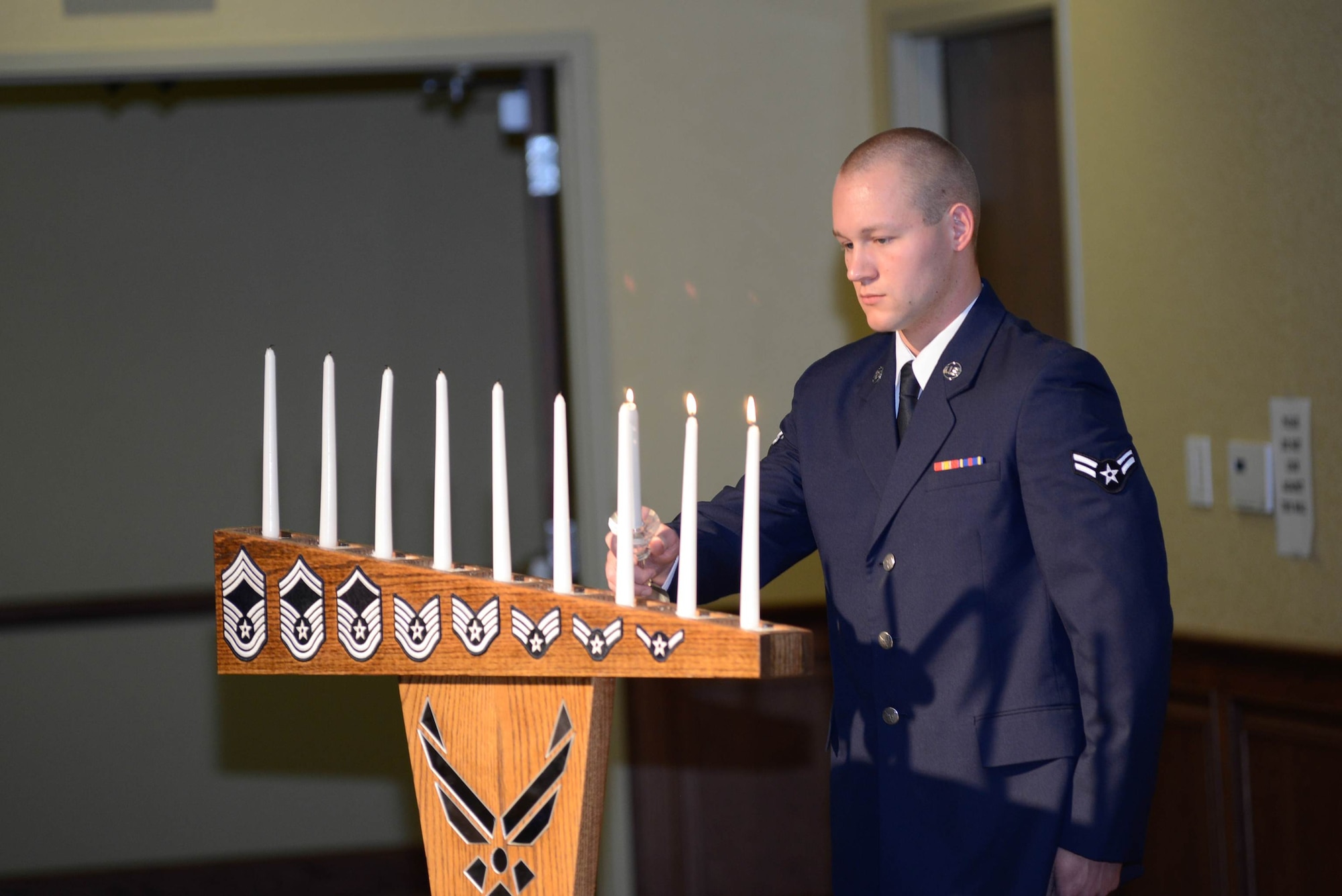 Airman 1st Class Devin Erne, 338th Training Squadron, lights the Airman 1st Class candle which denotes all of the ranks in which a chief master sergeant must attain prior to reaching the pinnacle Air Force enlisted rank during the Chiefs Recognition Ceremony Feb. 28, 2014, at the Bay Breeze Event Center, Keesler Air Force Base, Miss.  Keesler had four Airmen that were honored for attaining the rank of chief master sergeant.  Erne is the son of Chief Master Sgt. Kevin Erne, 338th TRS superintendent.  (Courtesy photo by Airman 1st Class Andrew Achong)