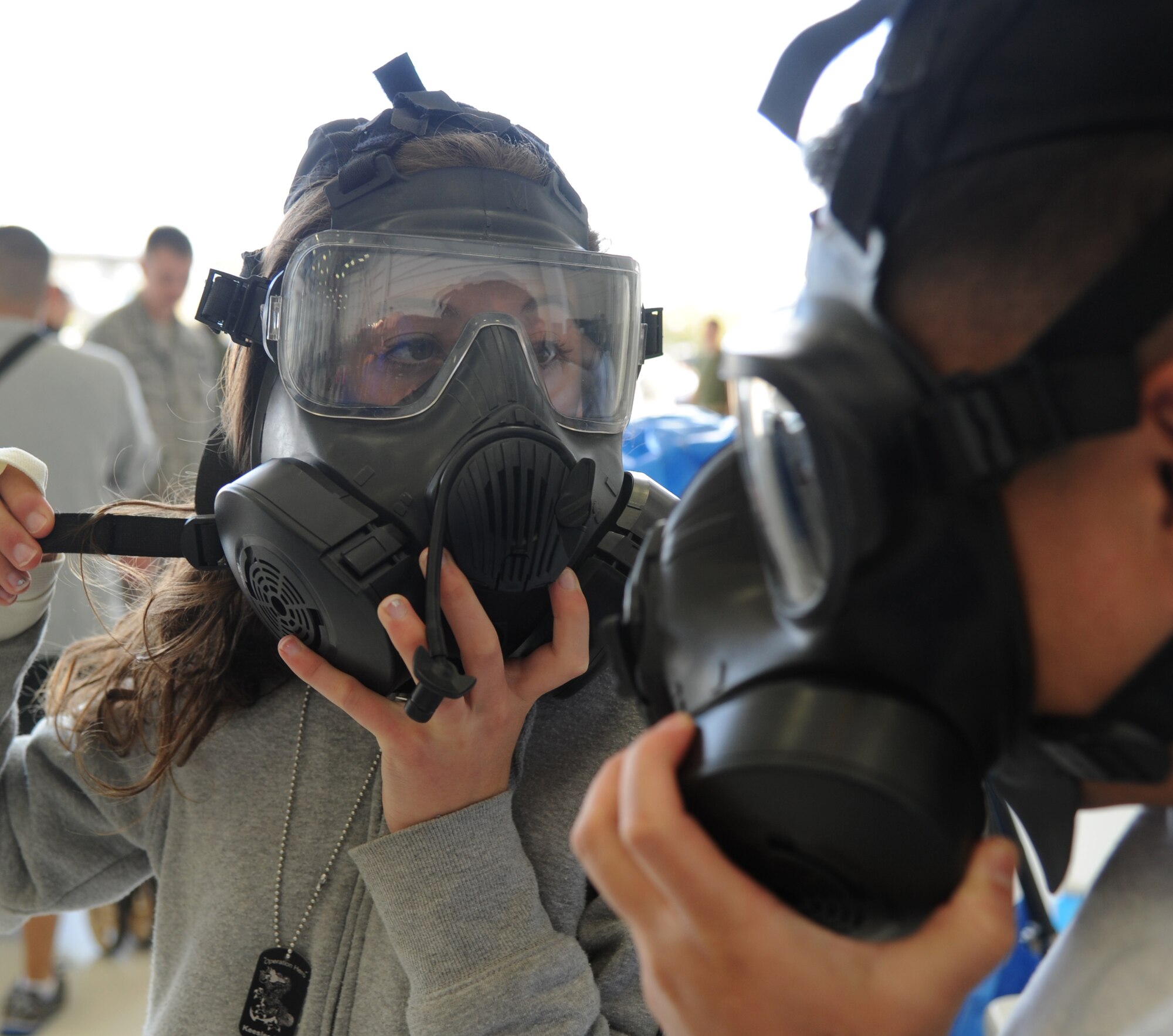 The daughter of Senior Master Sgt. Jonathan Sexton, 403rd Maintenance Squadron, fits into a chemical mask with the assistance of Staff Sgt. Jeffrey Sison, 81st Aerospace Medicine Squadron, during Operation Hero March 8, 2014, at Keesler Air Force Base, Miss.  The event was designed to help children better understand what happens when their parents deploy.  (U.S. Air Force photo by Kemberly Groue)