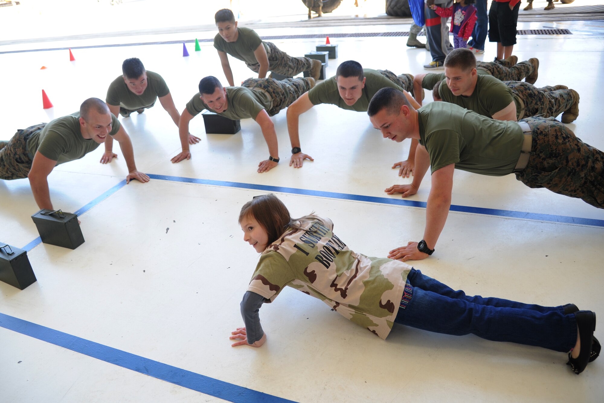 The grand-daughter of Master Sgt. Kathy Wheelock, 403rd Maintenance Squadron, challenges the Keesler Marine Detachment Marines to push-ups during Operation Hero March 8, 2014, at Keesler Air Force Base, Miss.  The event was designed to help children better understand what happens when their parents deploy.  (U.S. Air Force photo by Kemberly Groue)