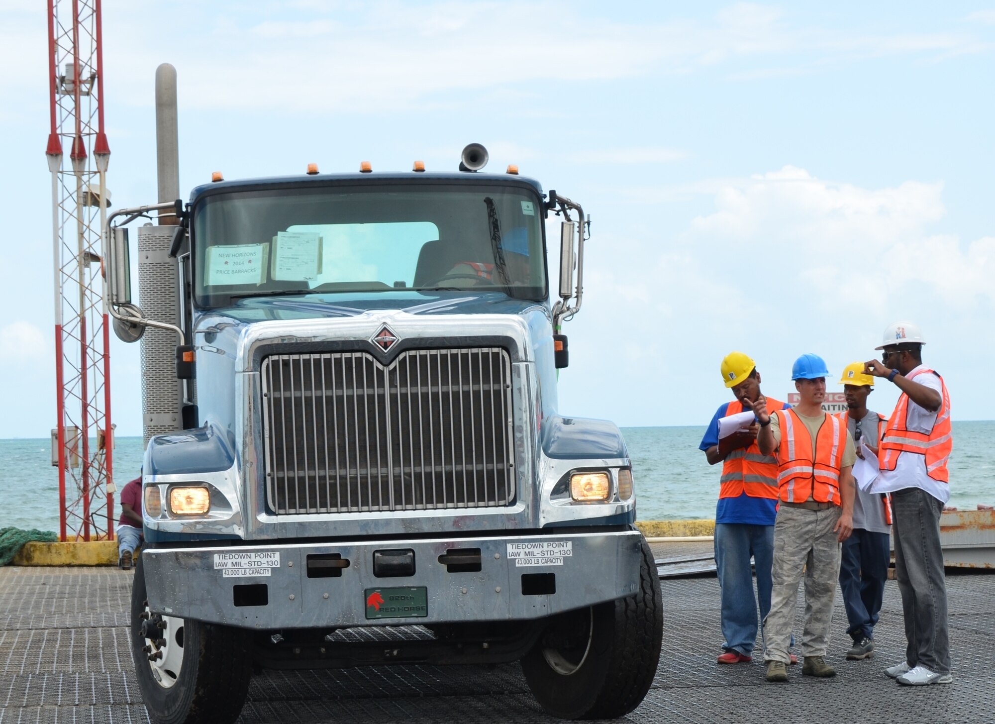 Staff Sgt. Odell Glasper, New Horizons Port Operations, discusses logistics with Port of Belize authorizes as he prepares to drive an 18-wheeler (semi-truck) off of the barge and onto the pier, March 8. Belizeans will begin noticing an influx of U.S. military equipment traveling from the Port of Belize to various locations throughout the country in support of New Horizons. (USAF photo by Master Sgt. Kelly Ogden/Released)