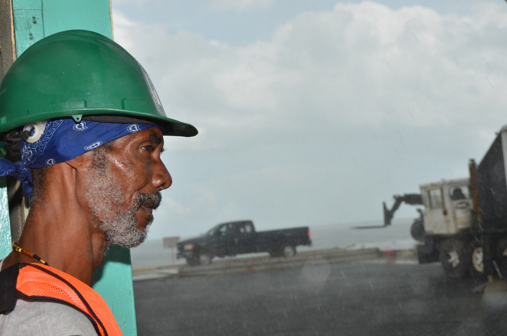 A Belizean contractor at the Port of Belize looks on as the downpour slows New Horizons equipment off-loading, March 8. The shipment, which left Cape Canaveral, Fla., March 1, included various construction and maintenance vehicles (tractor trailers, dump trucks, excavators, pickups, forklifts, backhoes and gas trucks) and a variety of shipping containers that will be used to support exercise requirements.