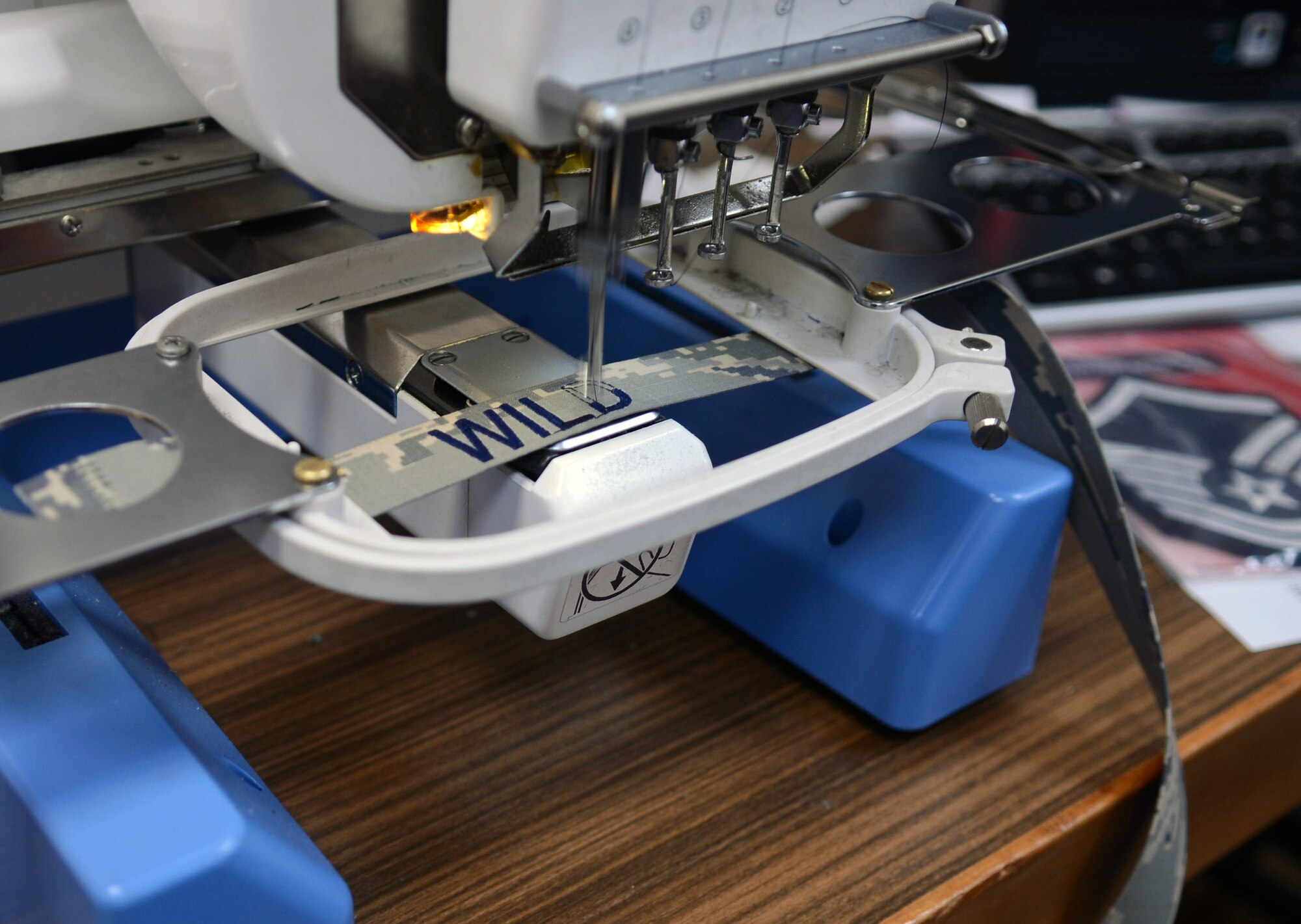 An embroidery machine sews a name onto a nametape Feb. 20, 2014, in the arts and crafts center on RAF Mildenhall, England. The embroidery machine can automatically embroider any name. The arts and crafts center is scheduled to move to the Bob Hope Community Center March 14, 2014. (U.S. Air Force photo by Airman 1st Class Kyla Gifford/Released)