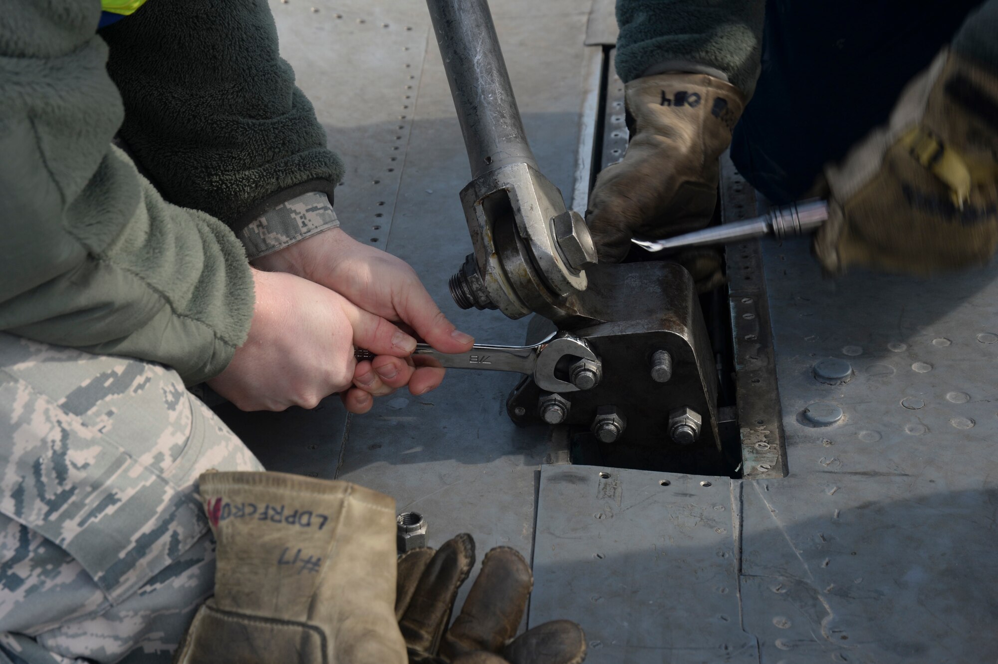 Airmen tighten bolts attached to the lift to an F-15B model jet during a Certification Crash Damaged Disabled Aircraft Recovery training on the flightline at Royal Air Force Lakenheath, England, March 8, 2014. The training exercise was an annual joint event between RAFs Mildenhall and Lakenheath which helped familiarize and requalify Airmen on aircraft lifting procedures. (U.S. Air Force photo by Airman 1st Class Nigel Sandridge/Released)