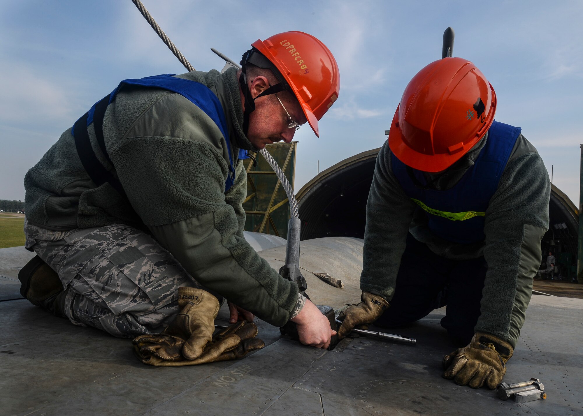 Tech. Sgt. Scott Douglass and Staff Sgt. Peter Strom, 48th Maintenance Squadron crash recovery, secure a lift cable to an F-15B jet during a Certification Crash Damaged Disabled Aircraft Recovery training on the flightline at Royal Air Force Lakenheath, England, March 8, 2014. The training exercise was an annual joint event between RAFs Mildenhall and Lakenheath which helped familiarize and requalify Airmen on aircraft lifting procedures. (U.S. Air Force photo by Airman 1st Class Nigel Sandridge/Released)