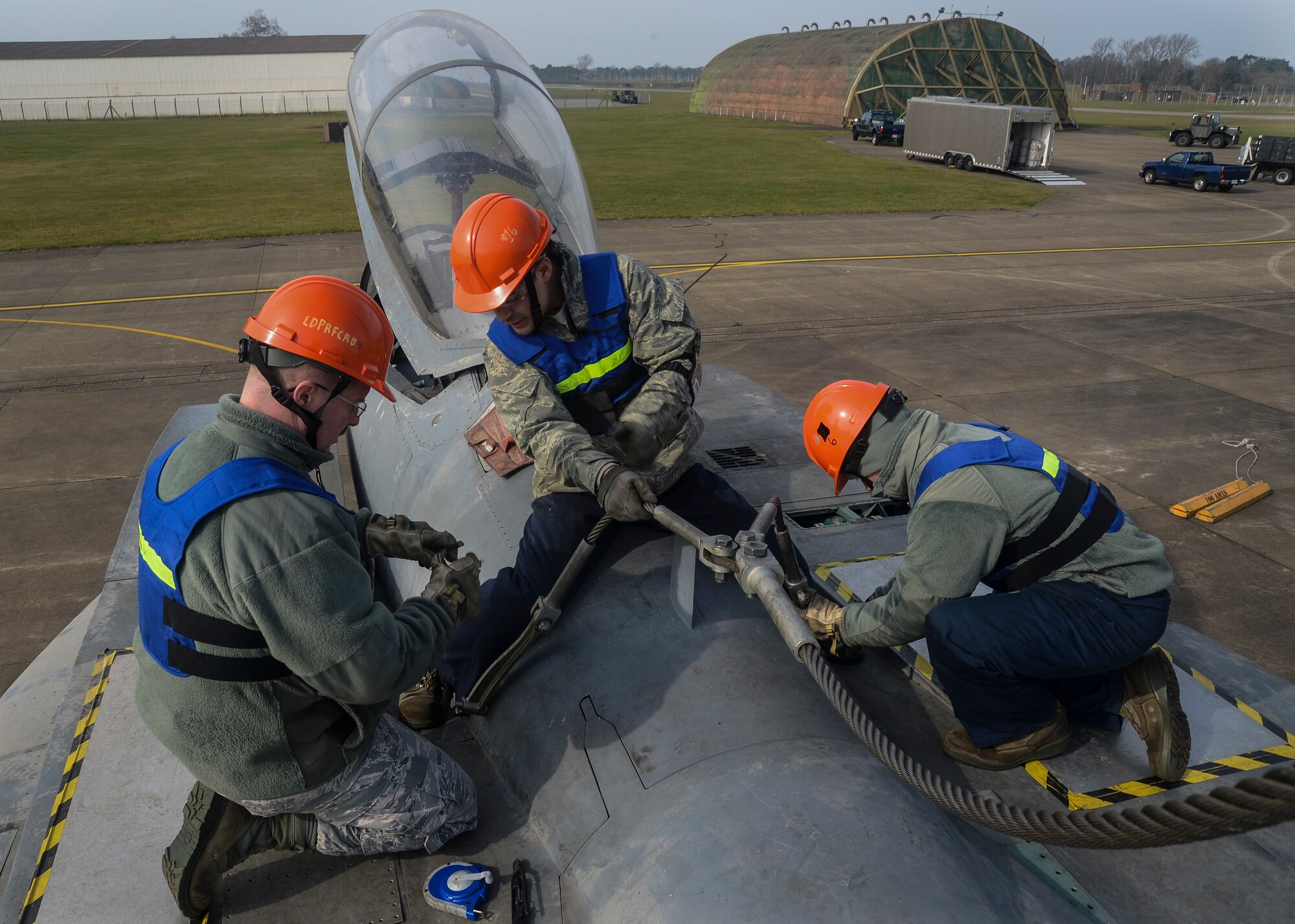 Staff Sgt. Erick Ballesterous, center, 48th Maintenance Squadron crash recovery instructor, assists re-certifying Airmen during Certification Crash Damaged Disabled Aircraft Recovery training on the flightline at Royal Air Force Lakenheath, England, March 8, 2014. The training exercise was an annual joint event between RAFs Mildenhall and Lakenheath which helped familiarize and requalify Airmen on aircraft lifting procedures. (U.S. Air Force photo by Airman 1st Class Nigel Sandridge/Released)