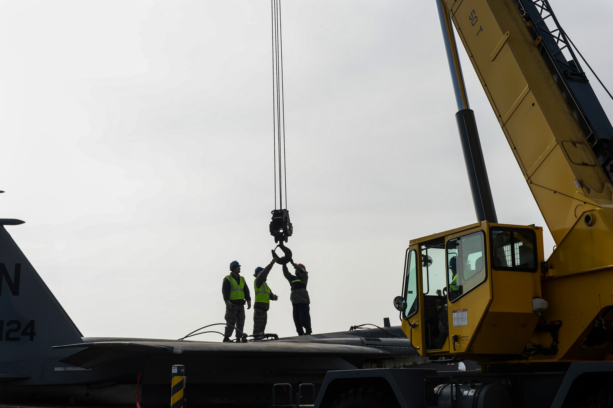 A hook is lowered from a crane to attachment points on an F-15B during Crash Damaged Disabled Aircraft Recovery training on the flightline at Royal Air Force Lakenheath, England, March 8, 2014. The training exercise was an annual joint event between RAFs Mildenhall and Lakenheath which helped familiarize and requalify Airmen on aircraft lifting procedures. (U.S. Air Force photo by Airman 1st Class Nigel Sandridge/Released)