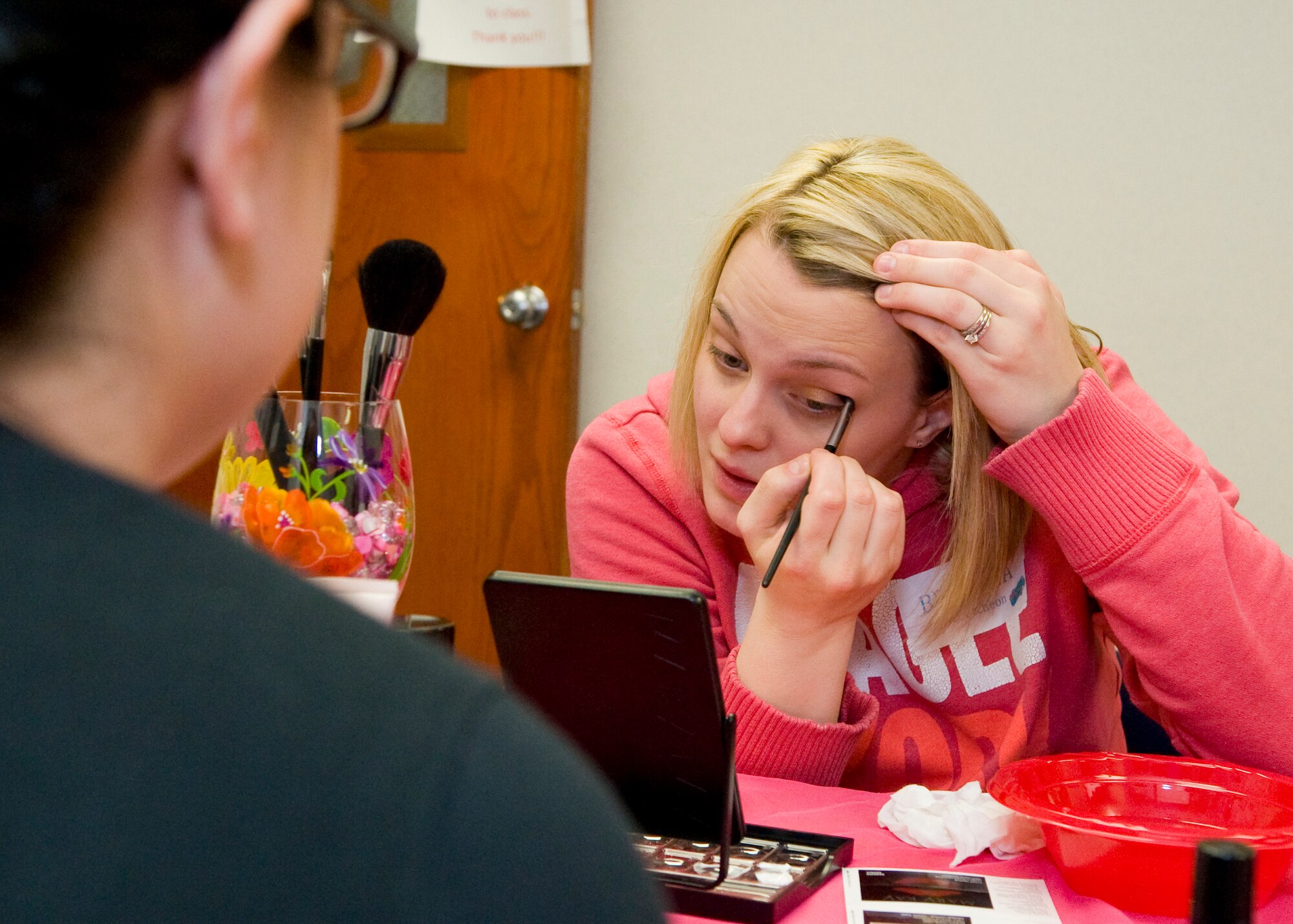 Brianna McCutcheon, wife of Senior Airman Steven McCutchen, 436th Civil Engineer Squadron electrician, applies eye shadow at the instruction of Cristal Andrews, Mary Kay independent beauty consultant, at a spa day for the spouses of deployed Team Dover Airmen, hosted by the Dover Key Spouses organization March 7, 2014, at Chapel Two on Dover Air Force Base, Del. McCucheon was one of 30 spouses to take advantage of the event. (U.S. Air Force photo/Airman 1st Class Zachary Cacicia) 