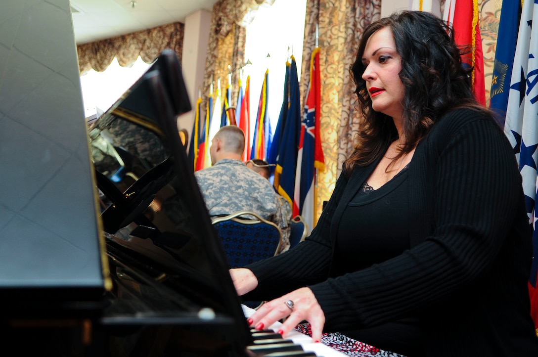 Mary McNutt, Regimental Memorial  Chapel Protestant music director, plays “America the Beautiful” as the crowd sings along during the 2014 National Prayer Breakfast at Fort Eustis, Va., March 6, 2014. The National Prayer Breakfast is an annual event dating back to 1953, designed to bring together communities by building relationships. (U.S. Air Force photo by Senior Airman Austin Harvill/Released) (Photo cropped, color balanced, and contrast adjusted to enhance image)