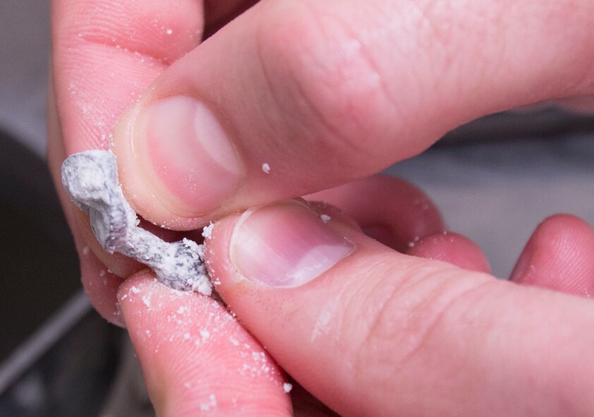 U.S. Air Force Tech. Sgt. Matthew Fitzgerald, 23d Aerospace Medicine Squadron NCO in charge of dental laboratory, rubs plaster residue from a gold crown mold at Moody Air Force Base, Ga., March 6, 2014. The dental laboratory created 135 gold and porcelain crowns last year. (U.S. Air Force photo by Senior Airman Tiffany M. Grigg/Released) 