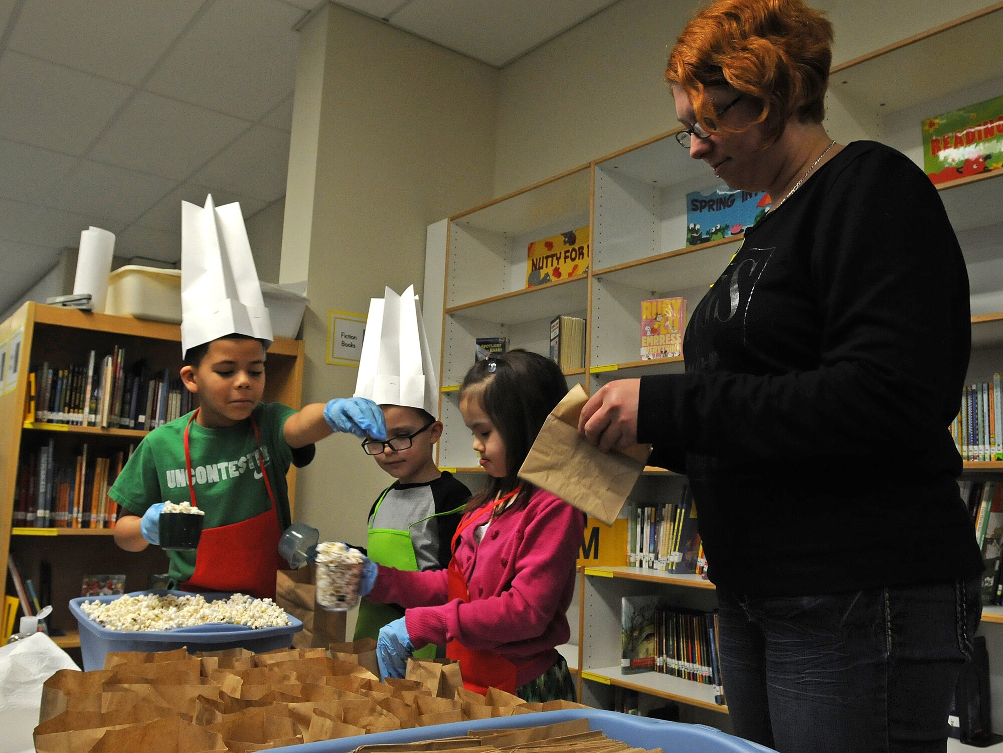 Lee Holman, wife of Staff Sgt. Jeremy Holman, 86th Vehicle Readiness Squadron vehicle mechanic, helps fill bags of popcorn at the reading café at Ramstein Elementary School during Read Across America week Mar. 3, 2014, Ramstein Air Base, Germany. Lee is one of many volunteers who came to participate in the celebration to promote reading to children. (U.S. Air Force photo/Airman 1st Class Holly Mansfield)