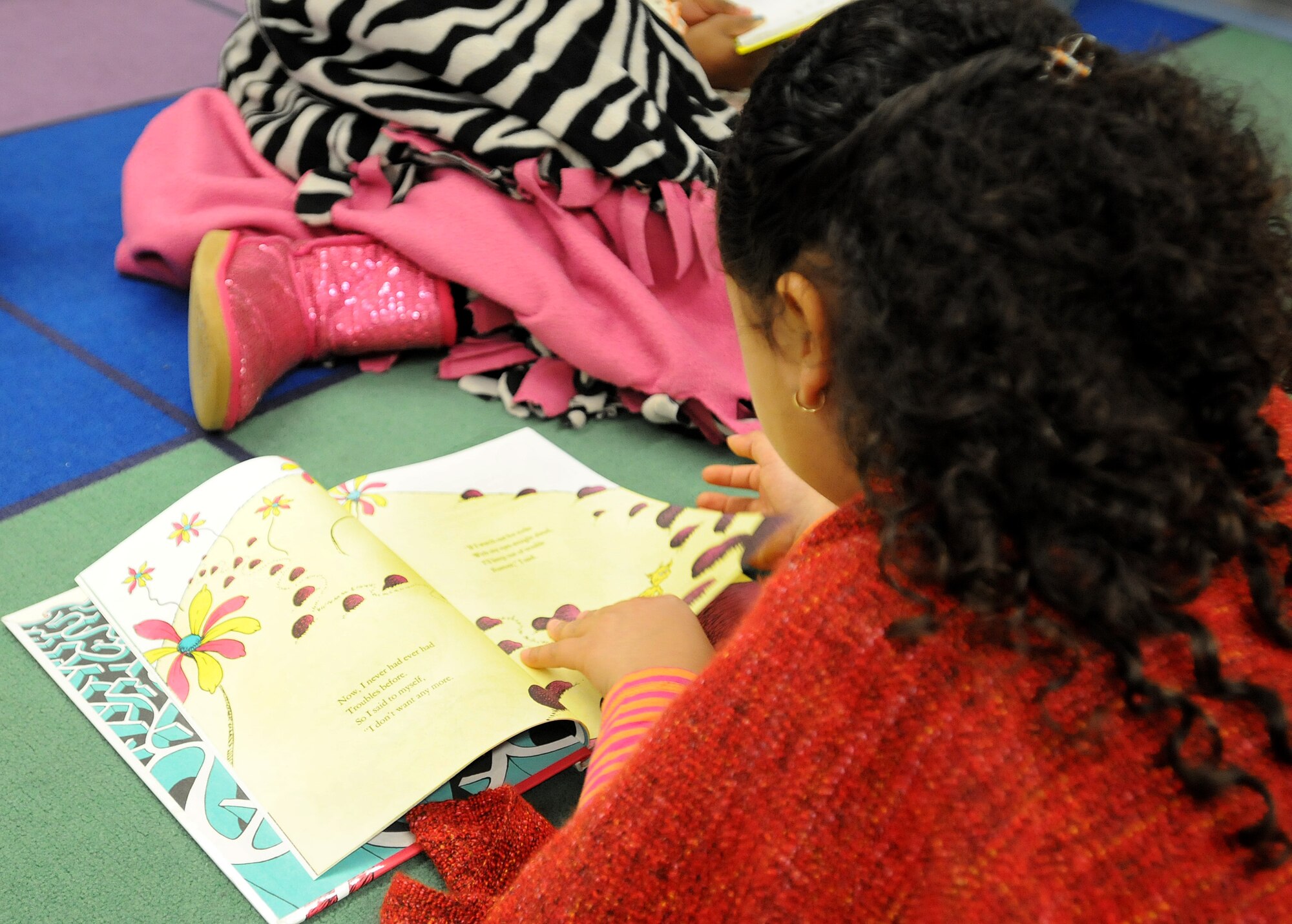 Jasmine Bass, daughter of Chief Master Sgt. Joanne Bass, 86th Operations Group superintendent, reads a book during Read Across America week Mar. 3, 2014, Ramstein Air Base, Germany. Read Across America is a week-long celebration, held the week of Dr. Seuss’ birthday, to teach children the importance of reading and education in schools across America and U.S. military installations overseas. (U.S. Air Force photo/Airman 1st Class Holly Mansfield)
