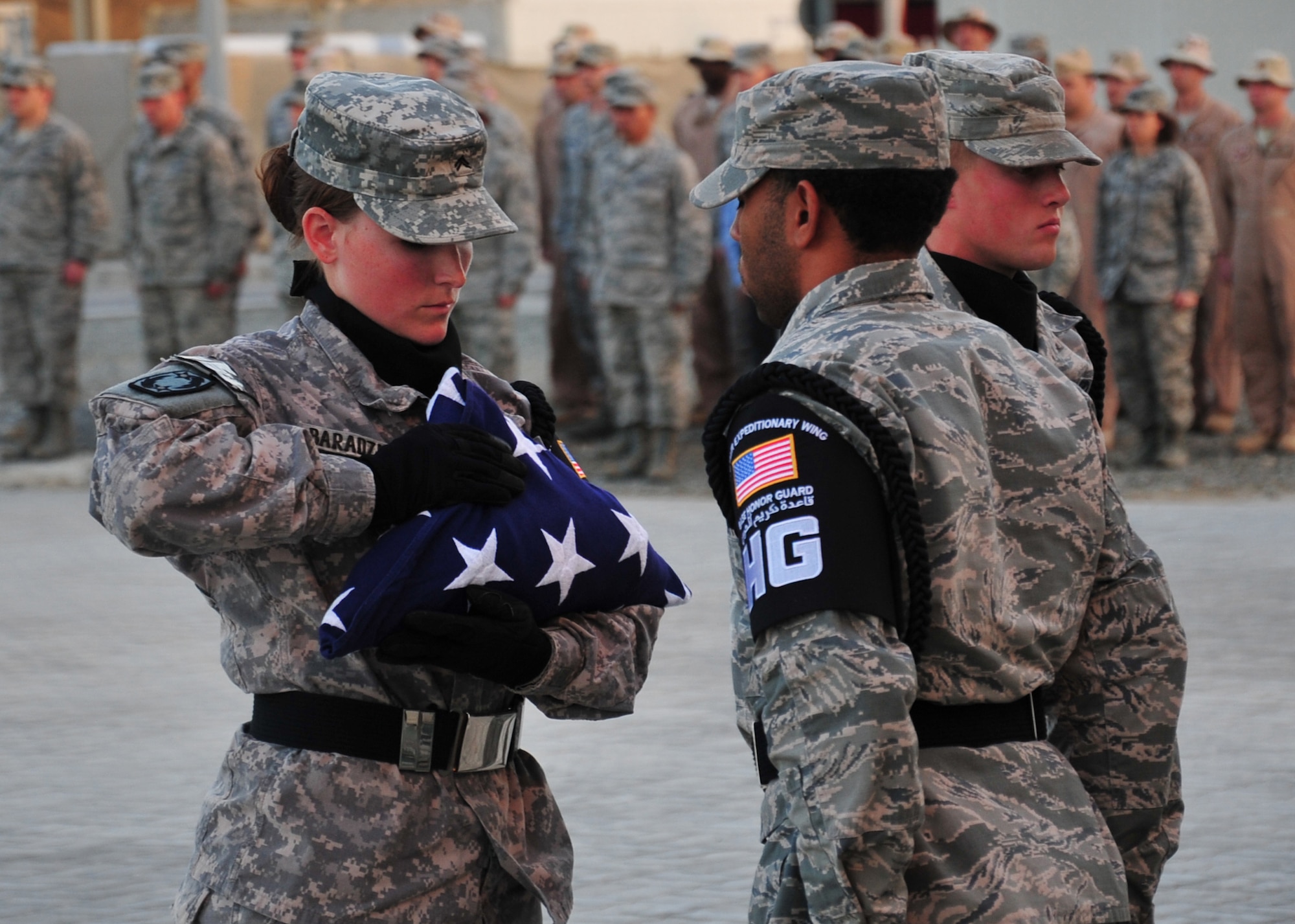 Army Cpl. Laura Baradziej, member of the base honor guard, dresses the flag during a retreat ceremony at an undisclosed location in Southwest Asia, March 7, 2014. (U.S. Air Force photo by Staff Sgt. Michael Means/Released)