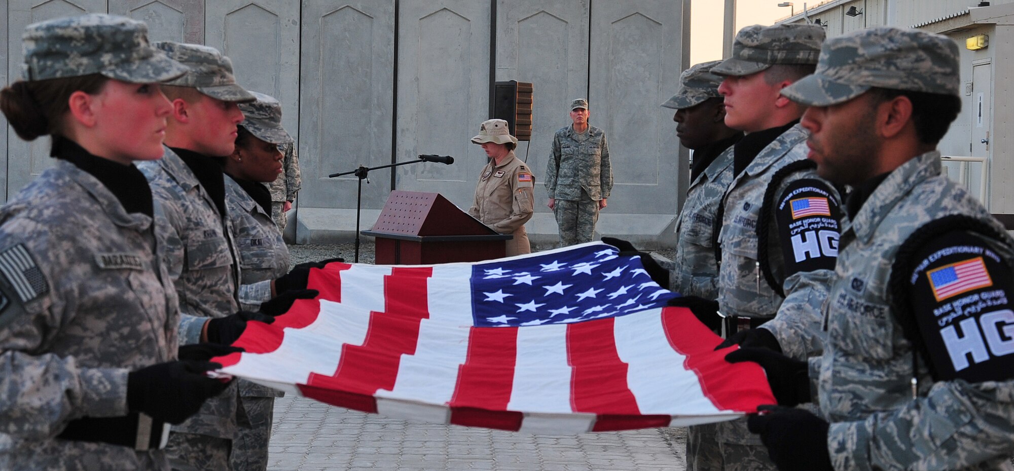 Capt. Alicia Cramer, 380th Expeditionary Operations Support Squadron officer in charge of current operations, reads the names of the women who have died this past year while serving their country as members of the base honor guard hold the flag at table top in honor of Women's History Month at an undisclosed location in Southwest Asia, March 7, 2014. (U.S. Air Force photo by Staff Sgt. Michael Means/Released)