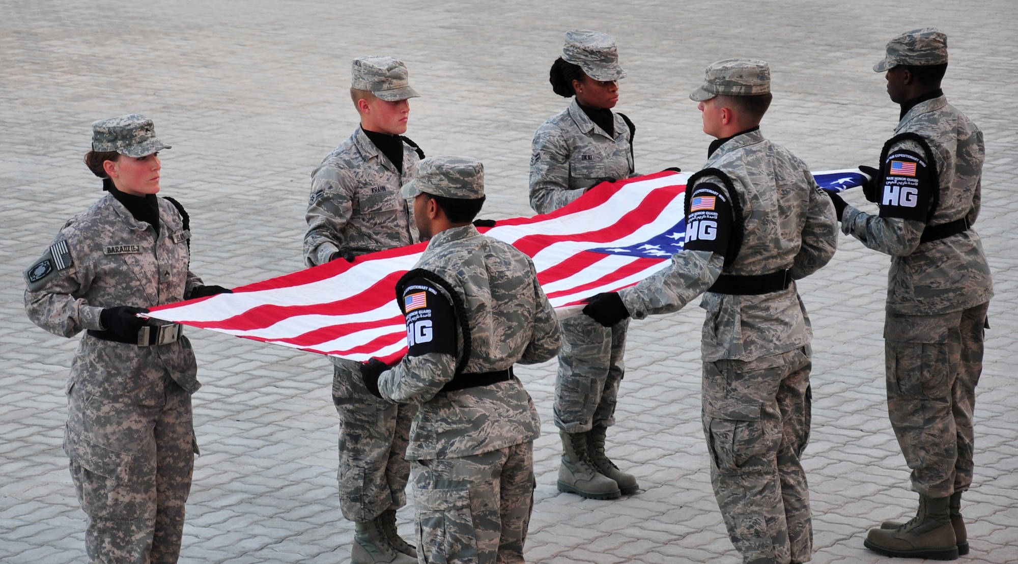 Members of the base honor guard hold the flag at table top as the names of military members who have gave their life for their country this month are read during a retreat ceremony at an undisclosed location in Southwest Asia, March 7, 2014. (U.S. Air Force photo by Staff Sgt. Michael Means/Released)