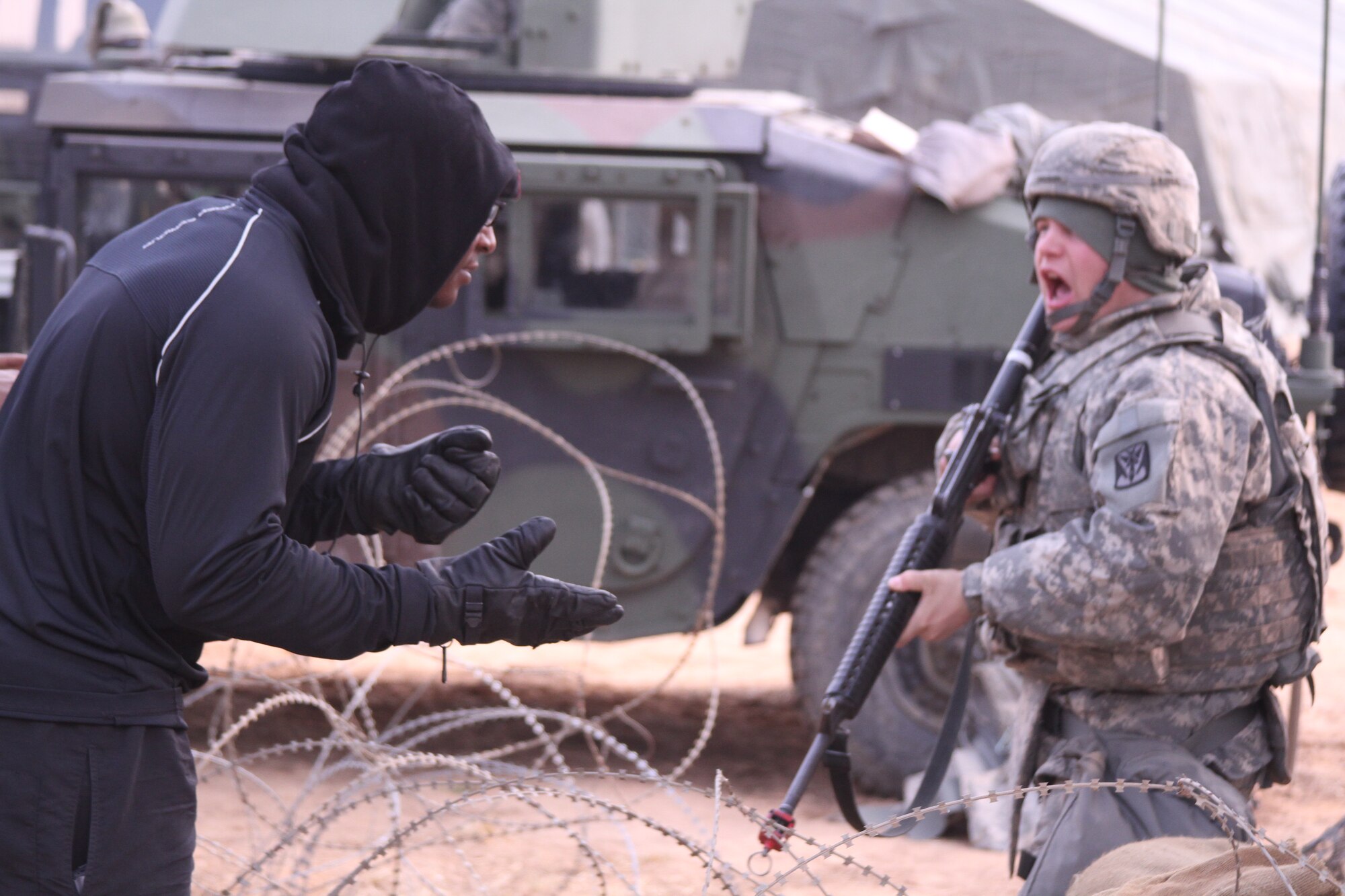 SEOSAN AIR BASE, Republic of Korea - Pfc. Austin Wecker (right), fire control crew member with Battery A, 6-52 ADA, warns Sgt. Ronald Jean-Batiste, who is role-playing as a civilian on the battlefield, to keep clear from their operations center during the Iron Resolve field training exercise at the Seosan AB, Feb. 24. (Photo by Pfc. Shin, Young-Jae, 6-52 ADA Public Affairs)
