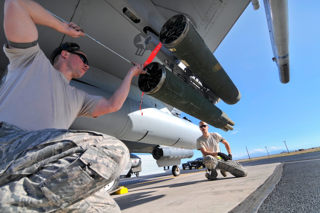 Air Force Tech. Sgt. Jason Wagner, foreground, and Air Force Airman 1st Class John Bybee lock Hydra-70 rockets with M257 illuminating flares into a LAU-131/A rocket launcher on an F-16C Fighting Falcon aircraft during Operation Snowbird on Davis-Monthan Air Force Base, Ariz., March 3, 2014. Wagner and Bybee are weapons loaders assigned to the New Jersey Air National Guard's 177th Fighter Wing.