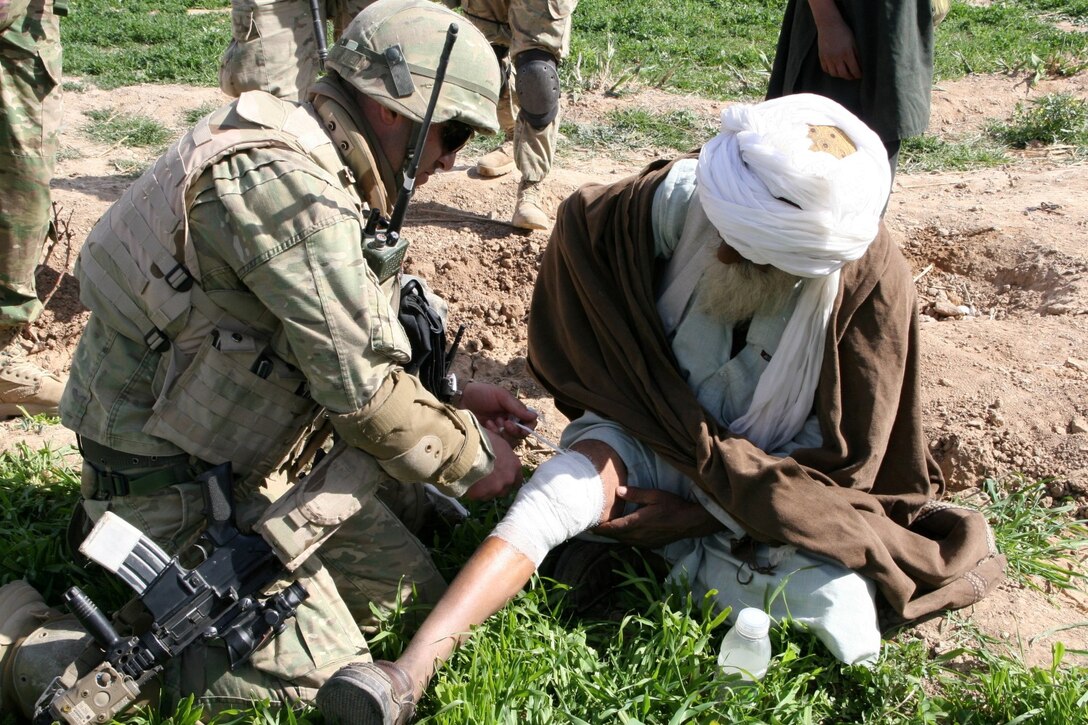 A soldier serving with the 31st Light Infantry Battalion from the Republic of Georgia offers medical assistance to a village elder after conducting a patrol through a village in the Now Zad District, Helmand Province, Afghanistan, March 7, 2014. The goal of the patrol was to clear the village of any possible insurgent threat, gather intelligence on the area and host a shura to talk to the local people.