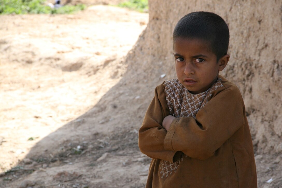 An Afghan child stands outside a compound and watches as soldiers with the 31st Light Infantry Battalion from the Republic of Georgia and a small group of U.S. Marines assigned to Alpha Company, Georgian Liaison Team-11, conduct a patrol through a village in the Now Zad District, Helmand province, Afghanistan, March 7, 2014. The goal of the patrol was to clear the village of any possible insurgent threat, gather intelligence on the area and host a shura to talk to the local people.