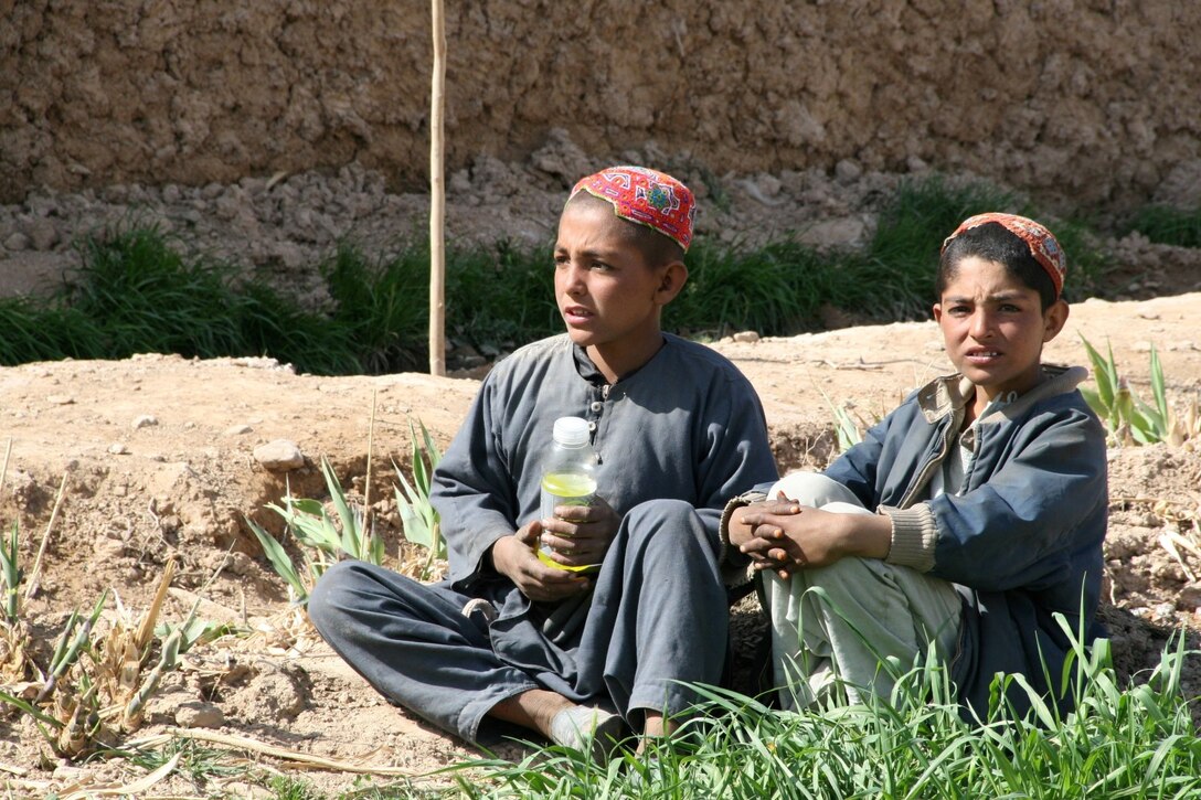 Afghan children sit outside a compound and watch as soldiers with the 31st Light Infantry Battalion from the Republic of Georgia and a small group of U.S. Marines assigned to Alpha Company, Georgian Liaison Team-11, host a shura in a village in Now Zad District, Helmand province, Afghanistan, March 7, 2014. The goal of the patrol was to clear the village of any possible insurgent threat, gather intelligence on the area and host a shura to talk to the local people.