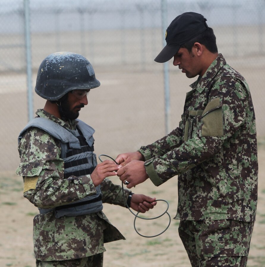 Sergeant Ahmaduuah, right, an instructor with Regional Corps Battle School, 7th Kandak, 215th Corps, Afghan National Army, explains to a student how to correctly prime a C-4 charge during an explosive ordnance disposal exercise aboard Camp Shorabak, Afghanistan, Mar. 5, 2014. The exercise was part of a four-week mortarman's course which instilled basic mortarman skills as well as taught explosive ordnance disposal skills to approximately 40 ANA soldiers. The ANA soldiers newly acquired training will give them an advantage on the battlefield as they return to their units throughout Afghanistan. (U.S. Marine Corps photo by Cpl. Cody Haas/ Released)