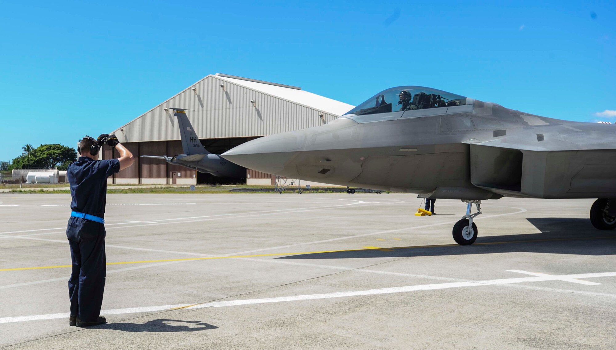 Senior Airman Trey MacLaughlin, a 525th Aircraft Maintenance Unit crew chief, marshals an F-22 Raptor into place on the flightline at Joint Base Pearl Harbor-Hickam, Hawaii, March 11, 2014. The Raptors are on temporary duty to Hawaii for “Operation Cope Thaw” from the 525th Fighter Squadron at Elmendorf Air Force Base, Alaska. (U.S. Air Force photo/Tech. Sgt. Terri Paden)