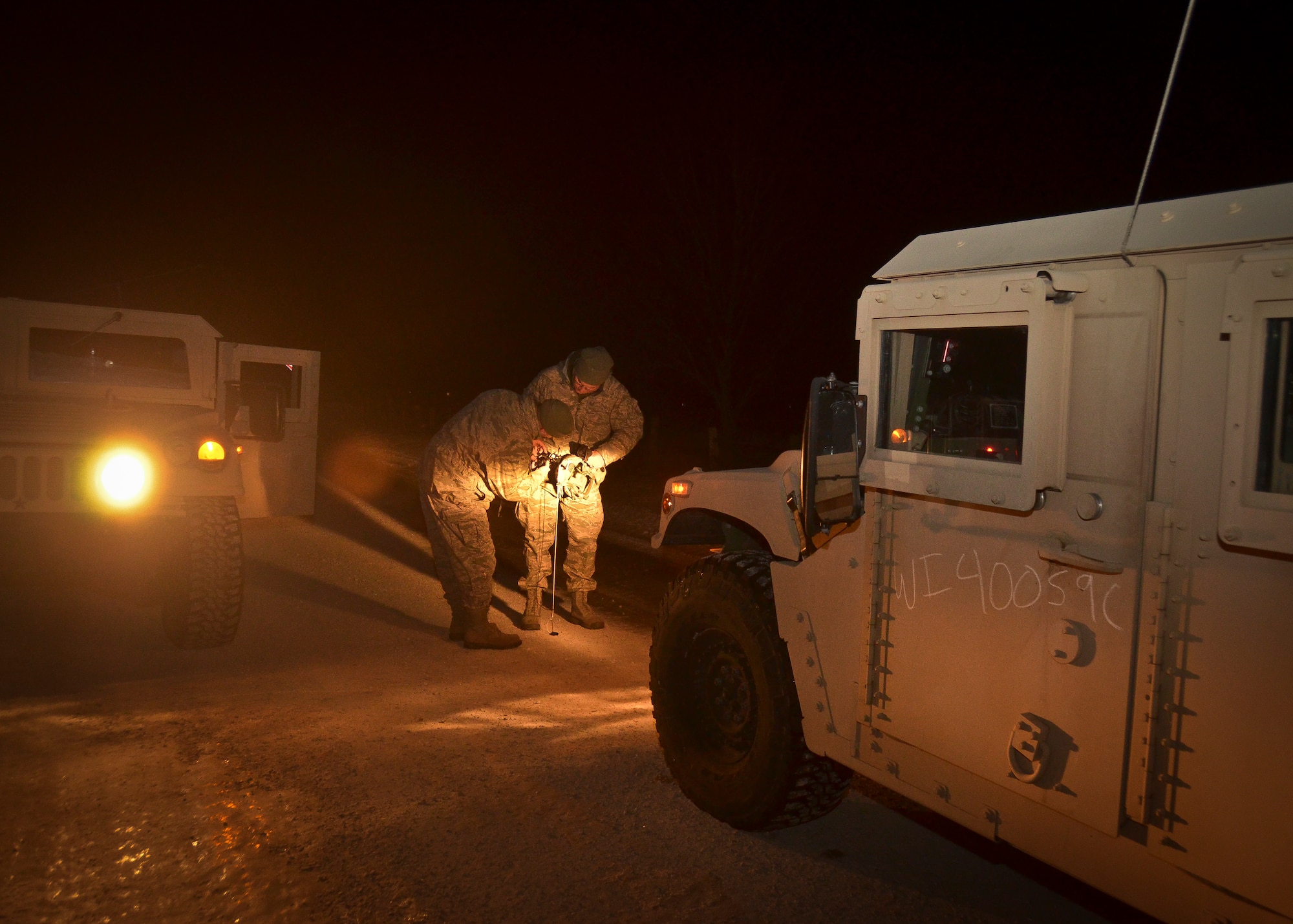 U.S. Airmen with the security forces squadron of the 128th Air Refueling Wing, Wisconsin Air National Guard, adjust their night vision components on their helmets in order to drive a Humvees from the 757th Transportation Battalion, U.S. Army Reserve, Milwaukee, in complete darkness on the roads of the Richard Bong State Recreation Area, Kansasville, Wis., Feb. 28, 2014.  The 128th Security Forces Squadron trained with U.S. Army Reserve tactical vehicles to qualify in nighttime driving and night vision training during the March unit training assembly.  (U.S. Air National Guard photo by Staff Sgt. Jenna V. Lenski/Released)