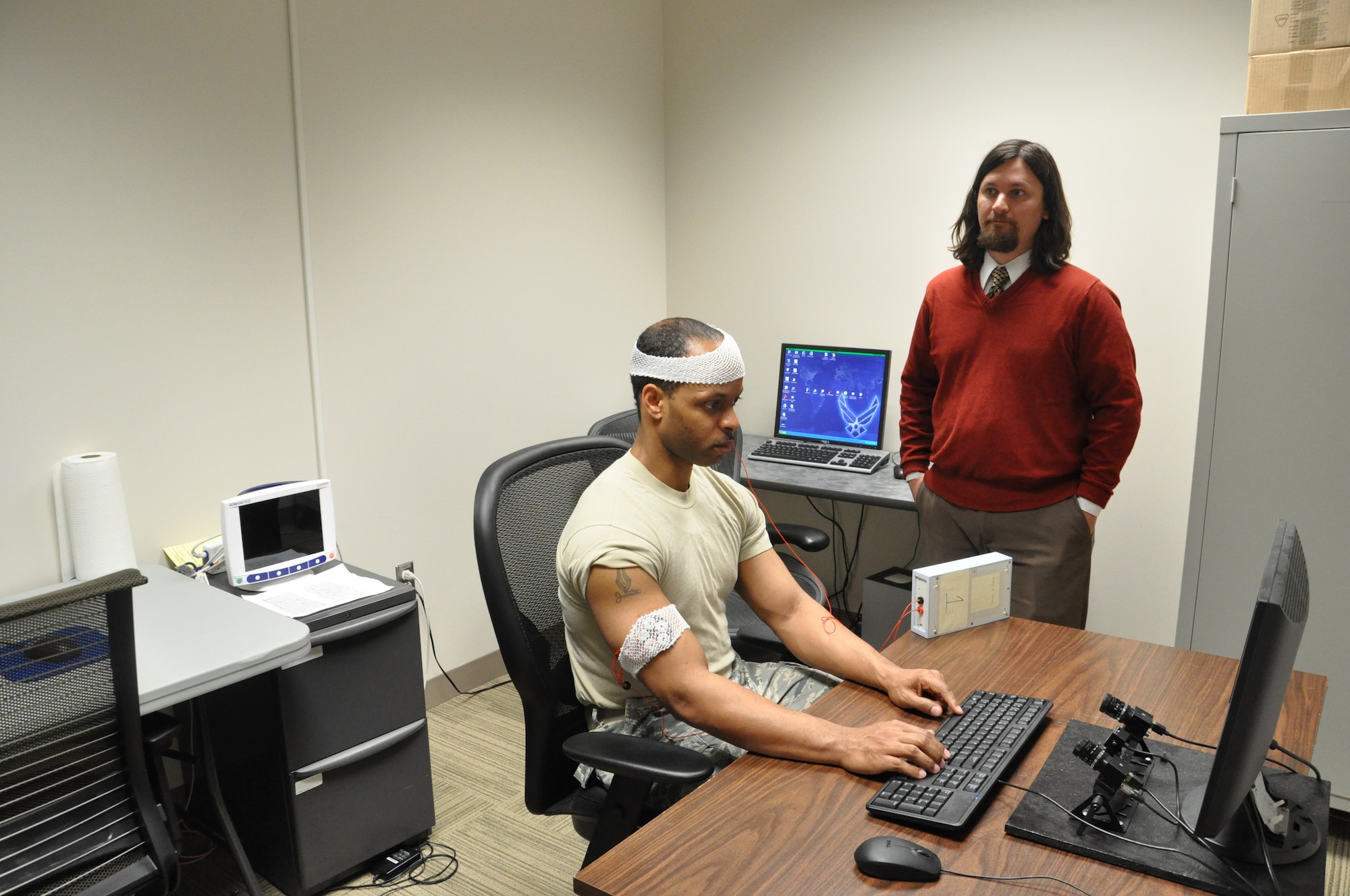 711 Human Performance Wing bioengineer, Dr. Andy McKinley (right), monitors the progress of volunteer Staff Sgt. William Raydon after applying an electric stimulation current to Raydon's brain as part of an Air Force non-invasive brain stimulation study conducted by researchers at the Air Force Research Laboratory's 711 Human Performance Wing.