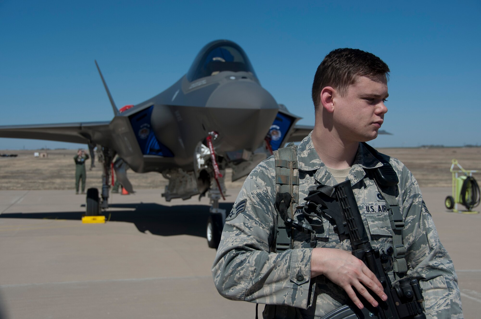 Senior Airman Ryan T. Albritton, 82nd Security Forces Squadron, stands just behind the cordon perimeter protecting the F-35 lightning II while Sheppard Airmen take the opportunity to see it up close March 11, 2014 at Sheppard Air Force Base, Texas from Eglin Air Force Base, Fla., as part of a hurricane evacuation exercise that would allow aircraft from Eglin to migrate to Sheppard if threatened by a hurricane. (U.S. Air Force photo/Tech. Sgt. Mike Meares)