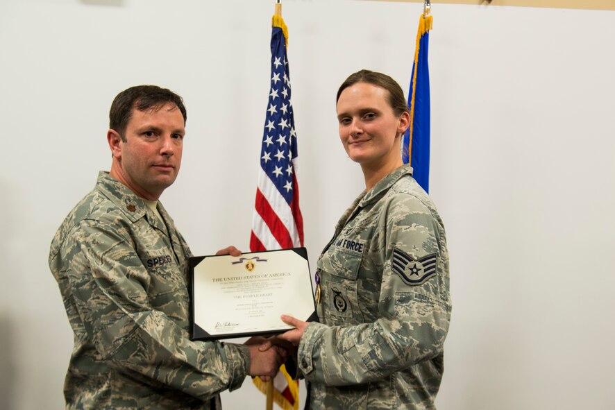 U.S. Air Force Staff Sgt. Haley Briggs, 824th Base Defense Squadron standards evaluation NCO in charge, receives a Purple Heart Medal certificate from Maj. Jeffrey Spencer, 824th BDS commander, March 12, 2014, at Moody Air Force Base, Ga. Family, friends and other members of the 824th BDS attended the ceremony to honor the Purple Heart recipient who earned the medal while performing gunner duties outside of Bagram Airfield, Afghanistan, in August 2012. (U.S. Air Force photo by Staff Sgt. Jamal D. Sutter/Released) 