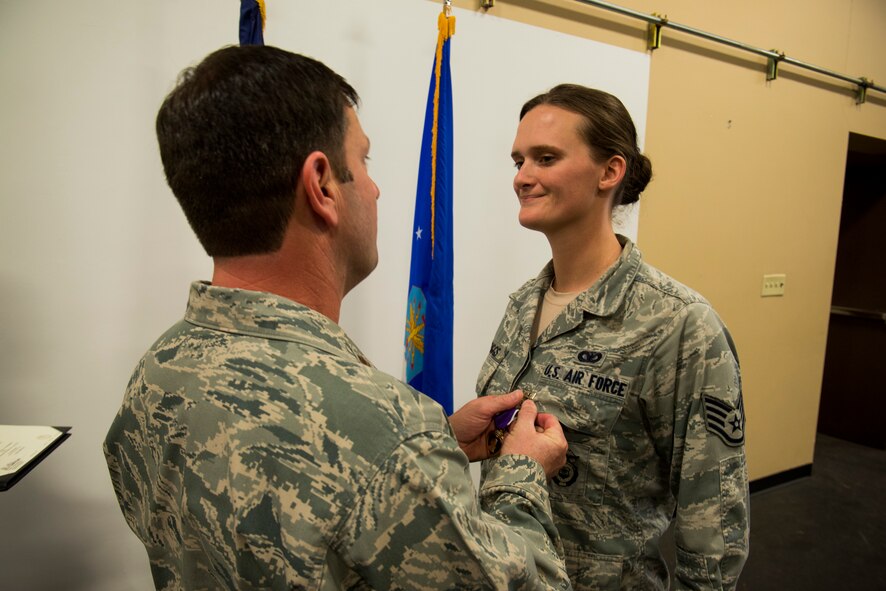 U.S. Air Force Staff Sgt. Haley Briggs, 824th Base Defense Squadron standards evaluation NCO in charge, receives a Purple Heart Medal from Maj. Jeffrey Spencer, 824th BDS commander, March 12, 2014, at Moody Air Force Base, Ga. Briggs earned the medal from an August 2012 incident when she sustained injuries from an improvised explosive device while performing gunner duties outside of Bagram Airfield, Afghanistan. (U.S. Air Force photo by Staff Sgt. Jamal D. Sutter/Released) 