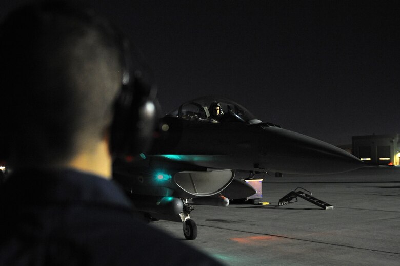 U.S. Air Force Capt. Daniel Wynn, a 77th Fighter Squadron F-16 Fighting Falcon pilot from Shaw Air Force Base, S.C., waits for a signal from Airman 1st Class David Cano-Mejia, a 20th Aircraft Maintenance Squadron crew chief from Shaw AFB, before taxiing onto the runway at Nellis Air Force Base, Nev., March 11, 2014. The Shaw AFB “Gamblers” sent 14 F-16s to participate in Red Flag 14-2. (Air Force photo/Staff Sgt. Chuck Broadway)