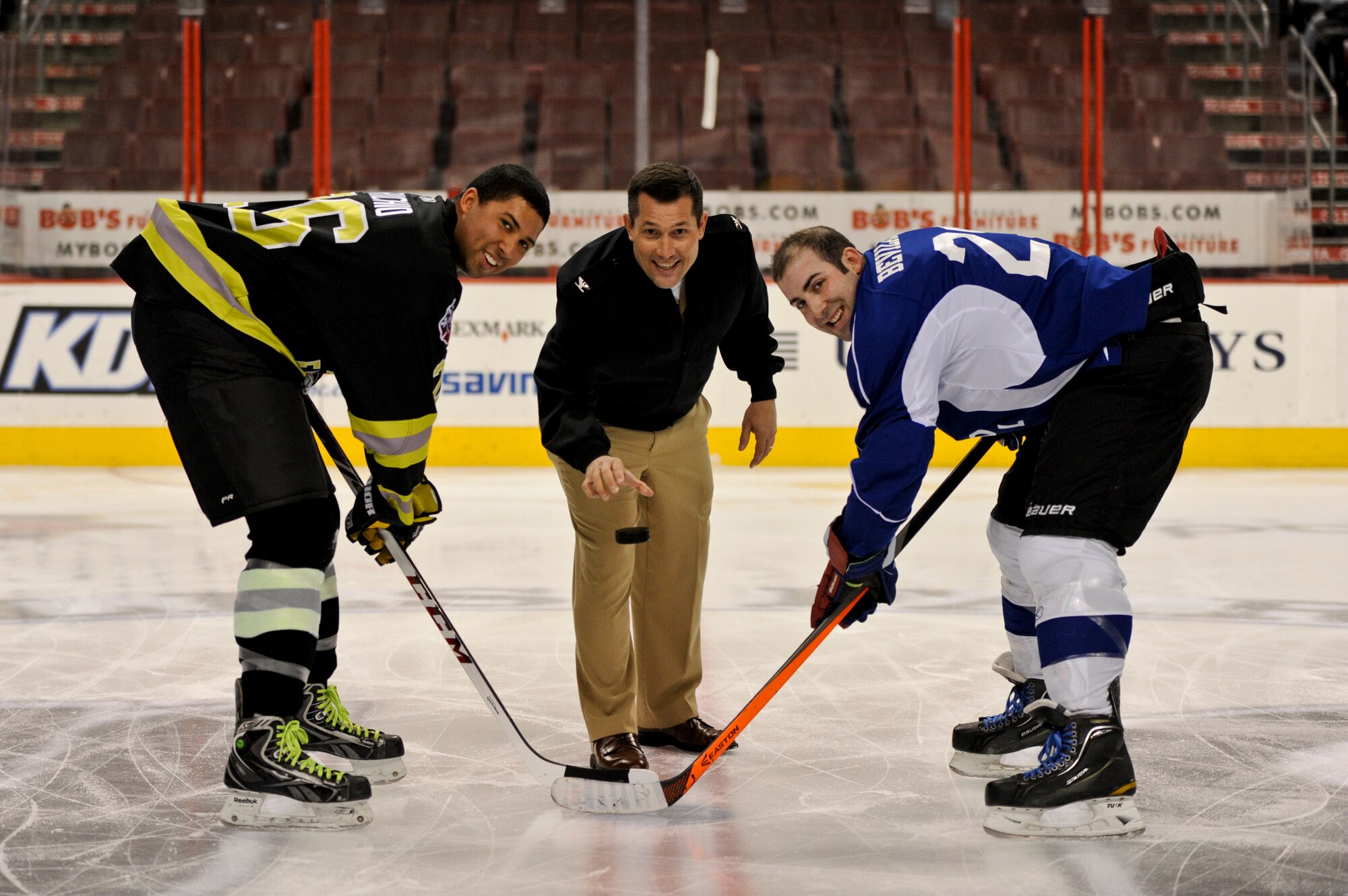 Navy Capt. Christopher Fletcher, JB MDL deputy commander, drops a hockey puck with the Philadelphia Fire Department and Joint Base McGuire-Dix-Lakehurst hockey team captains, Devon Richio (left) and Air Force Staff Sgt. James Bevilacqua, March 6, 2014, at the Wells Fargo Center in Philadelphia. JB MDL defeated PFD 4-3 during the special game meant to highlight the base’s hockey program resurgence. (U.S. Air Force photo by Airman 1st Class Sean M. Crowe/Released)