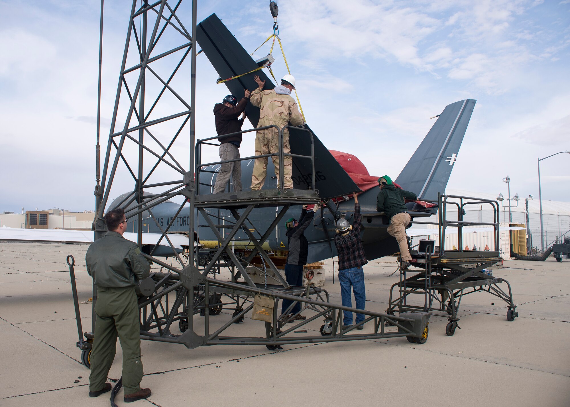 Navy Lieutenant commander Scott D. Rose watches the joint team of Navy, Beale Air Force Base, Calif., and Edwards AFB, Calif., personnel as they dismantle V-tail components of an Edwards RQ-4B Global Hawk Block 20 remotely piloted aircraft (tail number 2016) on Feb. 26. The Global Hawk T/N 2016 will be transferred to the Persistent Maritime Unmanned Aircraft Systems Program Office (PMA-262) located at Naval Air Station Patuxent River, Md., to be used in MQ-4C Triton device development and maintenance training. (U.S. Air Force photo by Ethan Wagner)