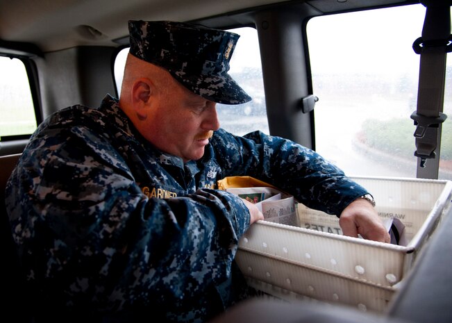 Master Chief Joseph Gardner, Naval Support Activity Charleston Command Master Chief , looks through a mail delivery bin while delivering mail as part of a 628th ABW leadership visit to the Official Mail Center March 7, 2014. Each month Joint Base Charleston commander Col. Jeffrey DeVore and his staff visit a different 628th agency and receive a hands-on tutorial on how to do a specific job. As mail room staff, Devore, Chief Master Sgt. Mark Bronson, 628th ABW command chief and Master Chief Petty Officer Joseph Gardner, Naval Support Activity Command Master Chief, learned to pitch, sort and deliver mail, metered and stamped. (U.S. Air Force photo/Staff Sgt. William A. O’Brien)