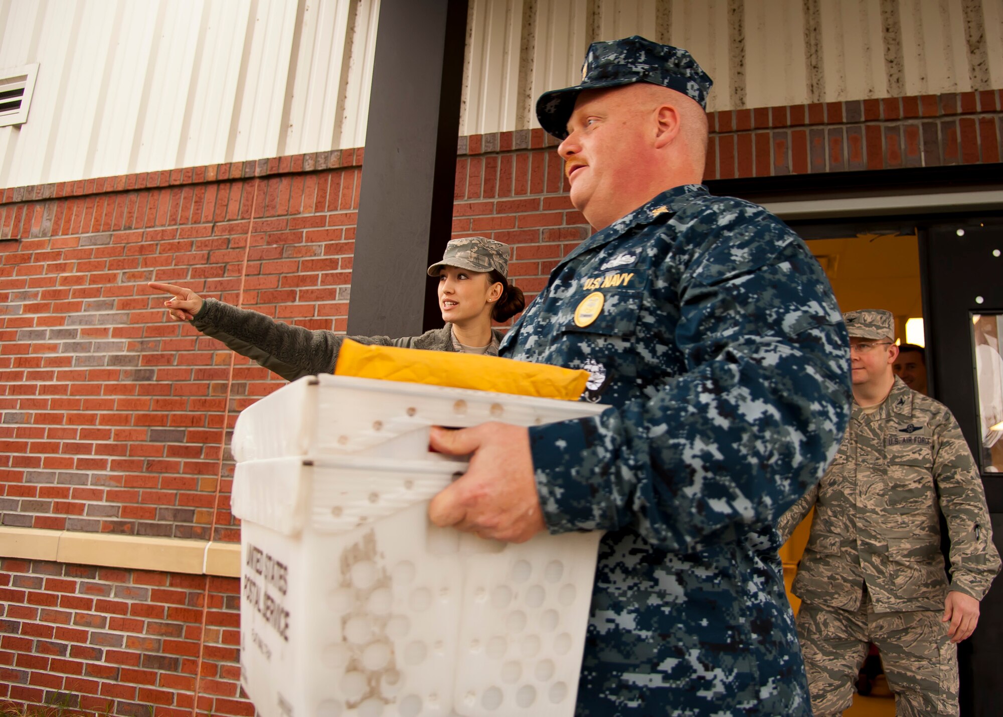 Airman 1st Class Jennie Short, 628th Communications Squadron official mail center, shows Naval Support Activity Charleston Command Master Chief Joseph Gardner, where to deliver a mail bin during a 628th ABW leadership visit to the OMC March 7, 2014. Each month Joint Base Charleston commander Col. Jeffrey DeVore and his staff visit a different 628th agency and receive a hands-on tutorial on how to do a specific job. As mail room staff, Devore, Chief Master Sgt. Mark Bronson, 628th ABW command chief and Command Master Chief Joseph Gardner, Naval Support Activity Command Master Chief, learned to pitch, sort and deliver mail, metered and stamped. (U.S. Air Force photo/Staff Sgt. William A. O’Brien)