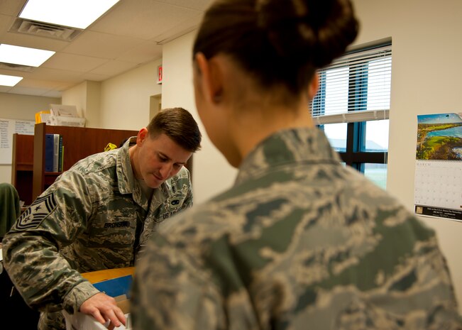 Chief Master Sgt. Mark Bronson, 628th Air Base Wing command chief, organizes mail prior to delivery as Airman 1st Class Jennie Short, 628th Communications Squadron official mail center looks on during a 628th ABW leadership visit to the OMC March 7, 2014. 
Each month Joint Base Charleston commander Col. Jeffrey DeVore and his staff visit a different 628th agency and receive a hands-on tutorial on how to do a specific job. As mail room staff, Devore, Chief Master Sgt. Mark Bronson, 628th ABW command chief and Master Chief Petty Officer Joseph Gardner, Naval Support Activity Command Master Chief, learned to pitch, sort and deliver mail, metered and stamped. (U.S. Air Force photo/Staff Sgt. William A. O’Brien)
