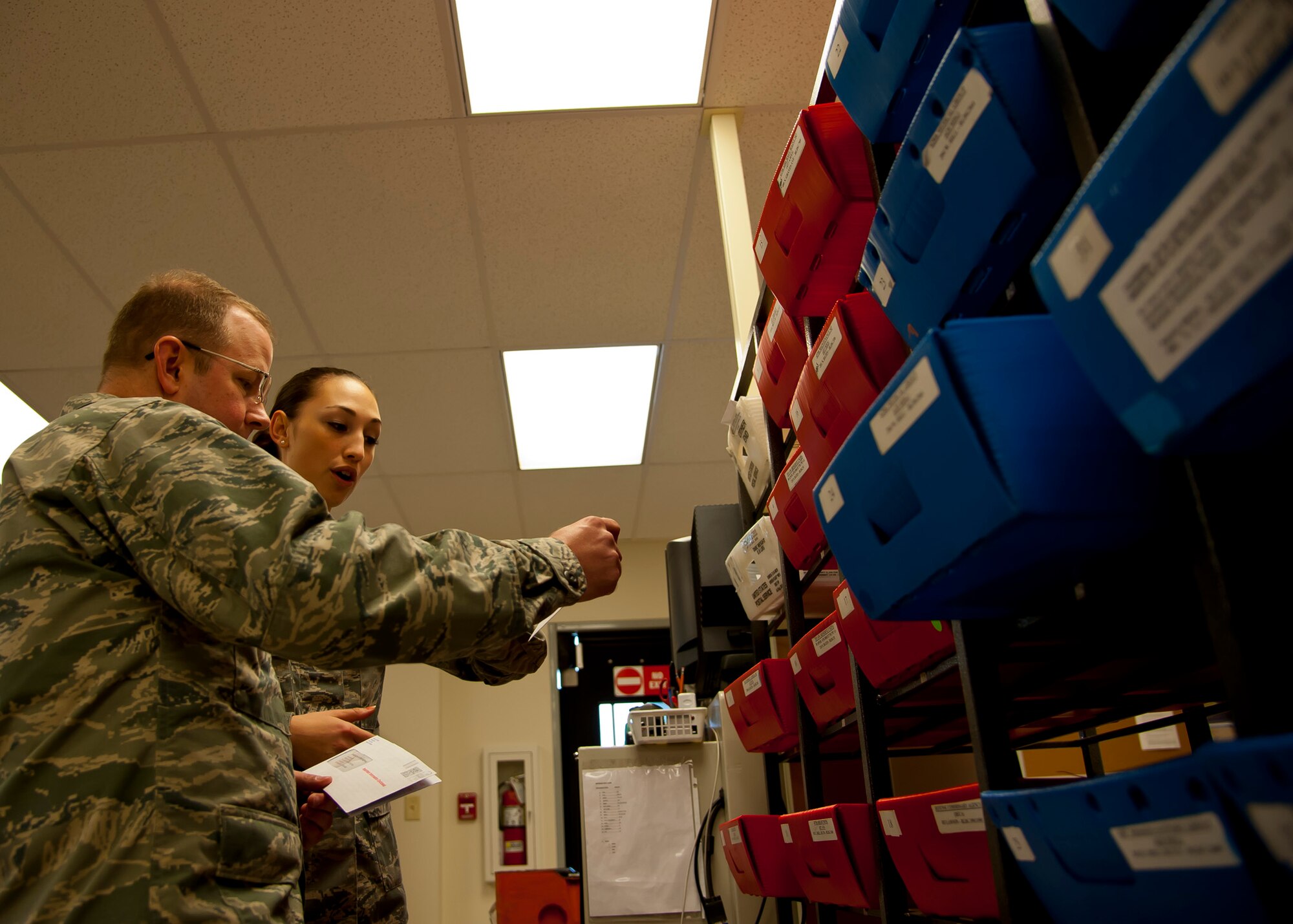 Airman 1st Class Jennie Short, 628th Communications Squadron official mail center, sorts mail with Col. Jeffery DeVore, Joint Base Charleston commander during a 628th Air Base Wing leadership visit to the OMC March 7, 2014. 
Each month DeVore and his staff visit a different 628th agency and receive a hands-on tutorial on how to do a specific job. As mail room staff, Devore, Chief Master Sgt. Mark Bronson, 628th ABW command chief and Master Chief Petty Officer Joseph Gardner, Naval Support Activity Command Master Chief, learned to pitch, sort and deliver mail, metered and stamped. (U.S. Air Force photo/Staff Sgt. William A. O’Brien)
