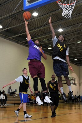 Senior Airman Divine Cox, center, jumps up for a shot against his opponent during an intermural game at Scott Air Force Base. (U.S. Air Force photo/Airman 1st Class Kiana Brothers)