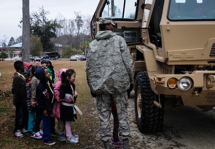 Airman 1st Class William Ely, 628th Medical Group medical material journeyman, shows children at Eagle Nest Elementary, vehicles Airmen use while deployed during career day March 5, 2014. Four Airmen from the 628th MDG spoke with the children about the Air Force and their jobs. 