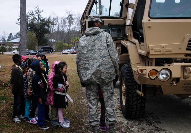 Airman 1st Class William Ely, 628th Medical Group medical material journeyman, shows children at Eagle Nest Elementary, vehicles Airmen use while deployed during career day March 5, 2014. Four Airmen from the 628th MDG spoke with the children about the Air Force and their jobs. 