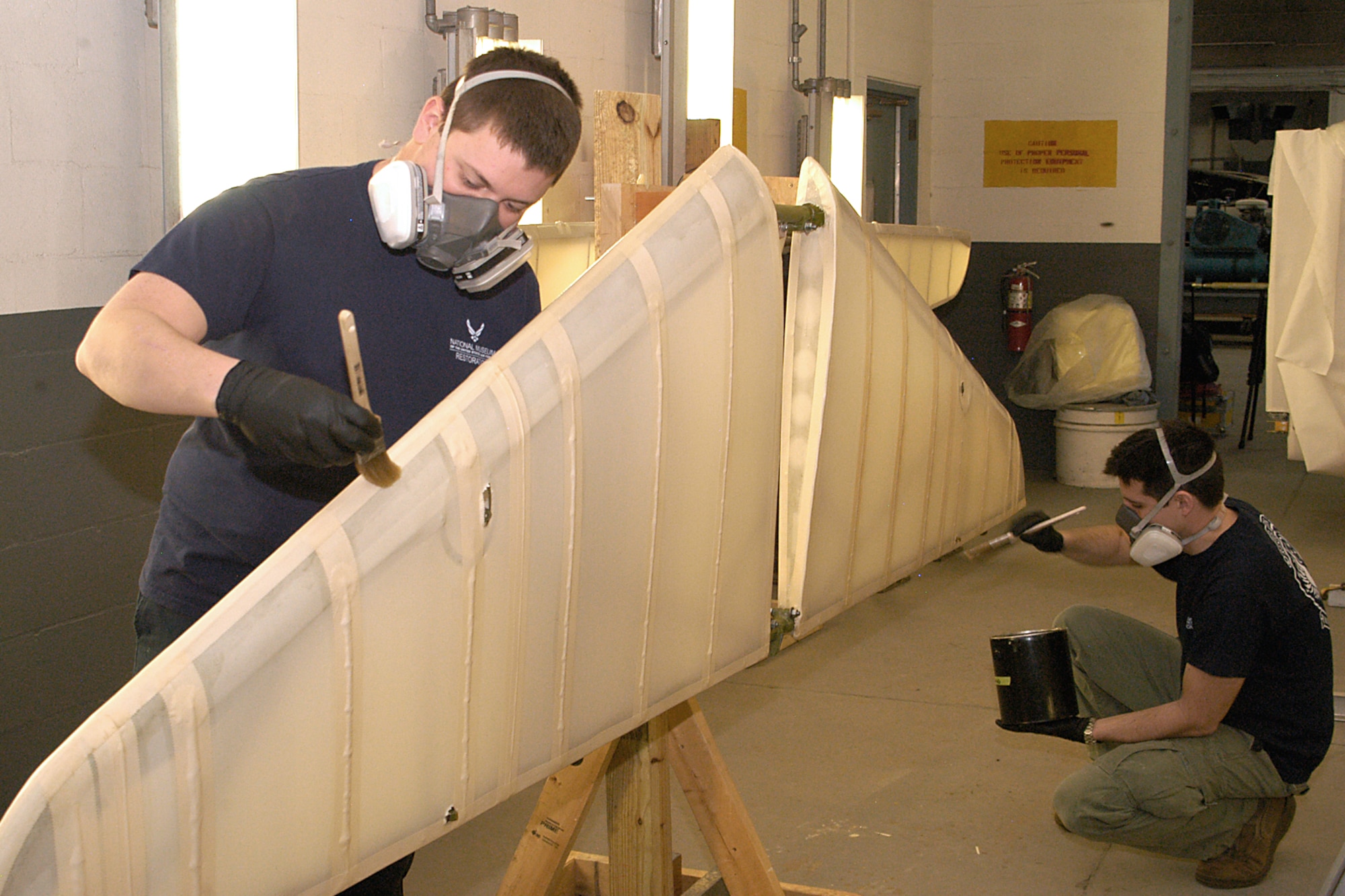 DAYTON, Ohio -- National Museum of the U.S. Air Force restoration specialists Nick Almeter and Casey Simmons apply aircraft dope which is a plasticized lacquer used to tighten and stiffen the fabric that is stretched over the airframe.  This procedure helps to weatherproof the aircraft and make the cotton airtight. Plans call for the aircraft to be part of an expanded Tuskegee Airman exhibit in the World War II Gallery at the National Museum of the U.S. Air Force. (U.S. Air Force photo by Ken LaRock)
