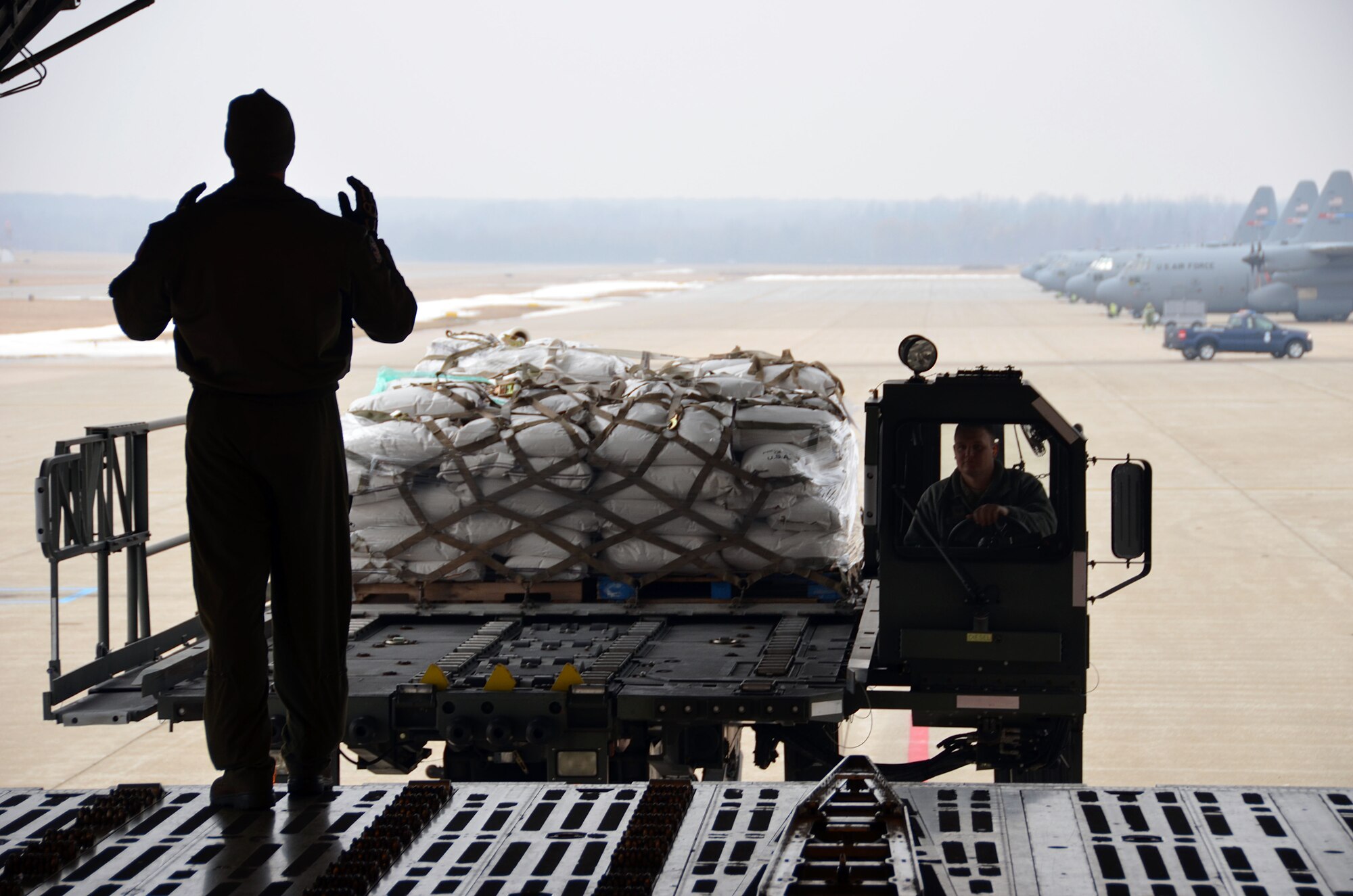 SMSgt. John Sandova, 337th Airlift Squadron Loadmaster, marshalls the pallets of corn into the Patriot Wing C-5 Galaxy at Youngstown Air Reserve Base, Ohio, March 8, 2014. The 11-man Patriot Wing crew delivered 20 tons of humanitarian aid to Guatemala City, Guatemala, March 9. (U.S. Air Force photo/SSgt. Kelly Goonan) 