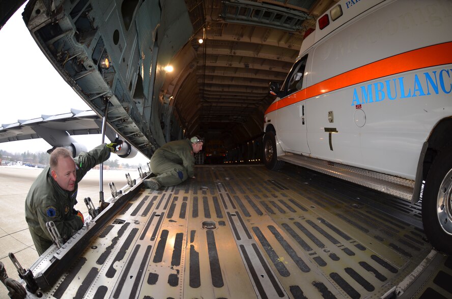 MSgt. Steven Duplessis, 439th Airlift Control Flight Loadmaster, and TSgt. Adam Weber, 439th Aircraft Maintenance Squadron Crew Chief, ensure the ambulance is properly winched into the Patriot Wing C-5 Galaxy at Youngstown Air Reserve Base, Ohio, March 8, 2014. The 11-man Patriot Wing crew delivered 20 tons of humanitarian aid to Guatemala City, Guatemala, March 9. (U.S. Air Force photo/SSgt. Kelly Goonan) 