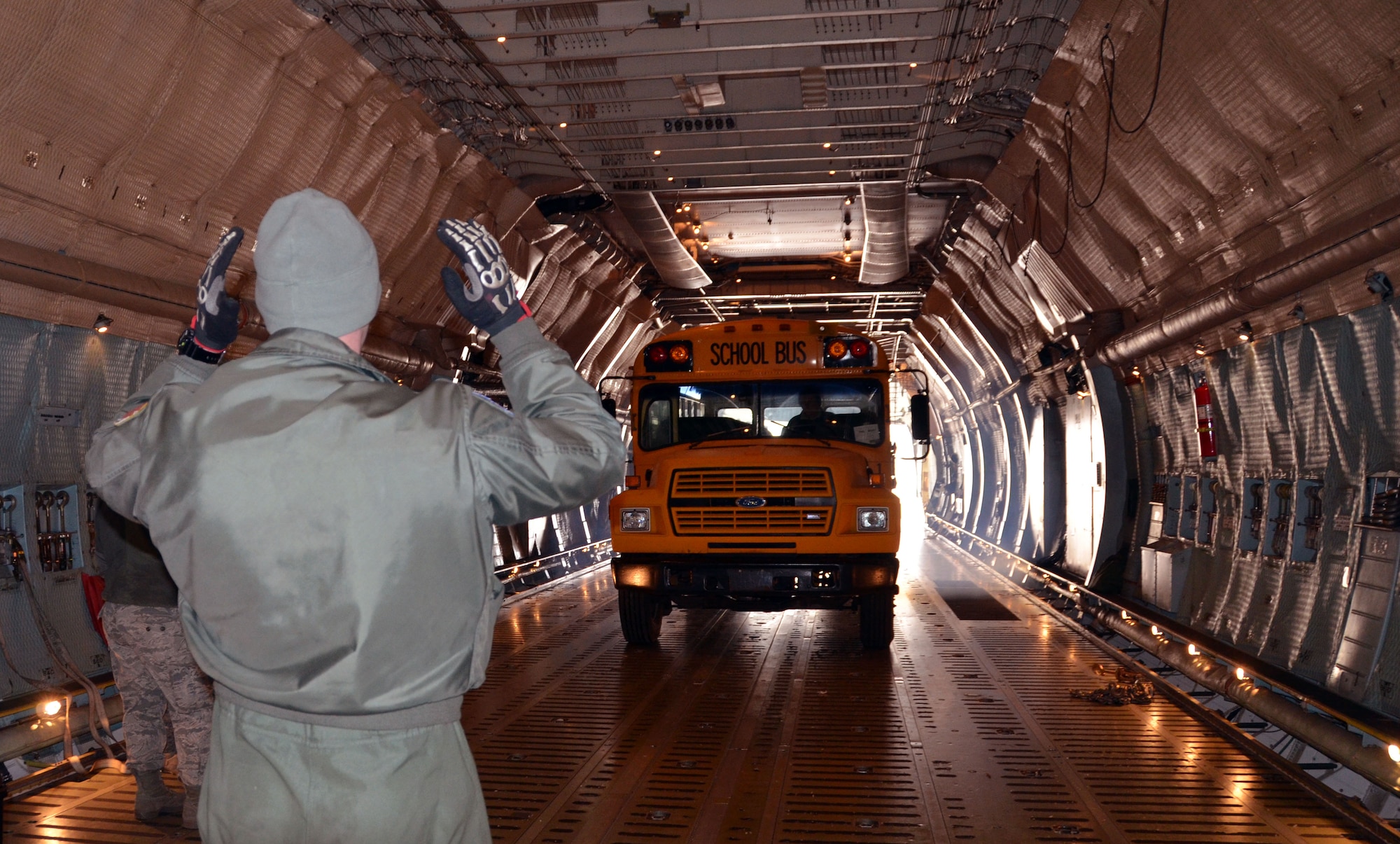 TSgt. Daniel Orcutt, 337th Airlift Squadron Loadmaster, marshalls a school bus onto the Patriot Wing C-5 Galaxy at Youngstown Air Reserve Base, Ohio, March 8, 2014. The 11-man Patriot Wing crew delivered 20 tons of humanitarian aid to Guatemala City, Guatemala, March 9. (U.S. Air Force photo/SSgt. Kelly Goonan) 
