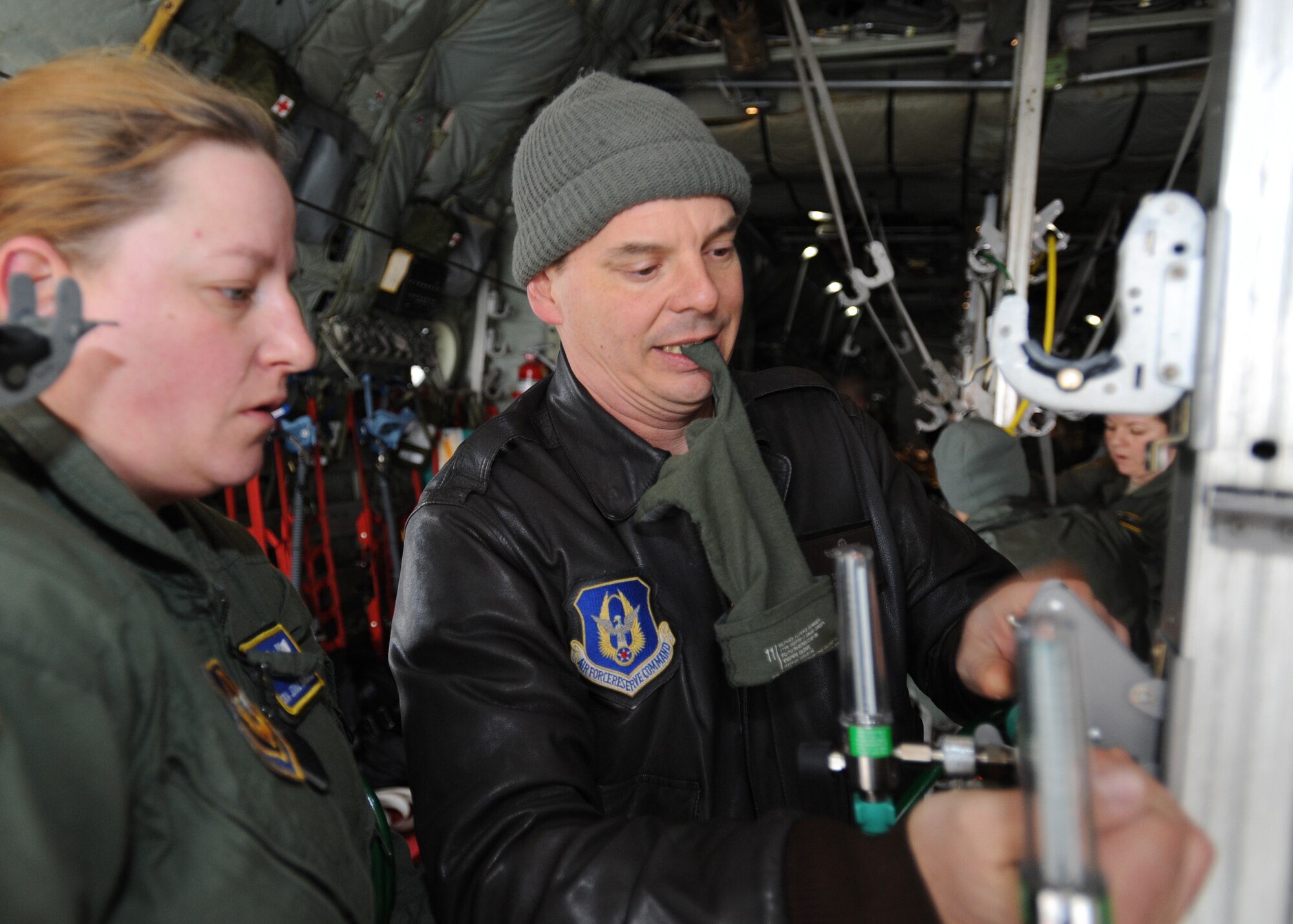 Senior Master Sgt. Anthony Staut, an aeromedical evacuation technician instructor with the Pope Field Aeromedical Evacuation Formal Training Unit, shows Senior Airman Jennie Marshall, a student from the 349th AES, Travis AFB, Calif., a new way to attach an oxygen minilator to a C-130H aircraft stanchion during a final flight evaluation at Pope Field, N.C., on Mar. 7, 2014.  The final flight evaluation is the culmination of nearly seven months of training that Airmen undergo while earning the aeromedical evacuation certification.  (U.S. Air Force photo by Tech. Sgt. Peter R. Miller)